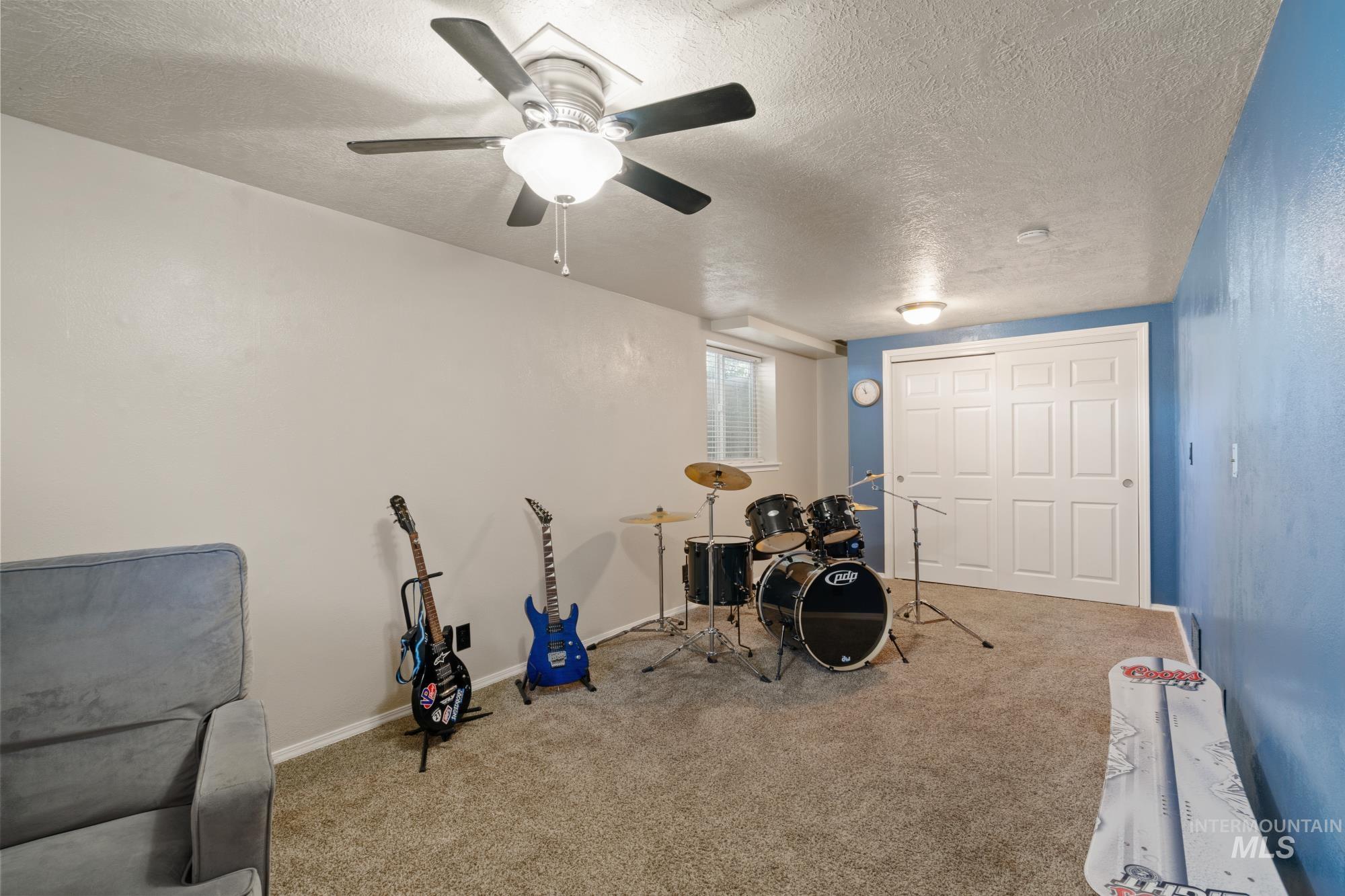 Playroom featuring a textured ceiling, carpet floors, and a ceiling fan