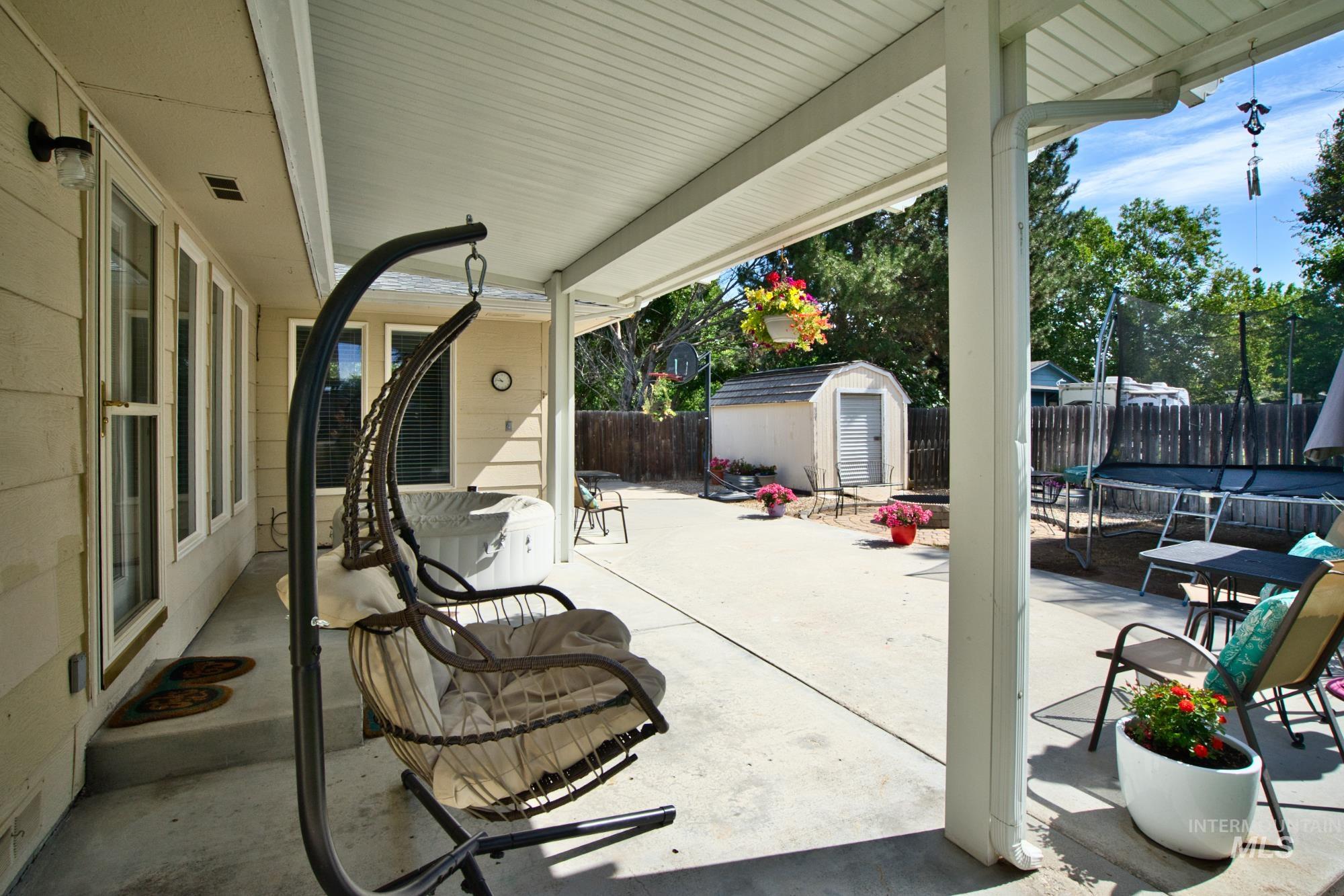 Fenced backyard featuring a trampoline, a patio, and a storage shed