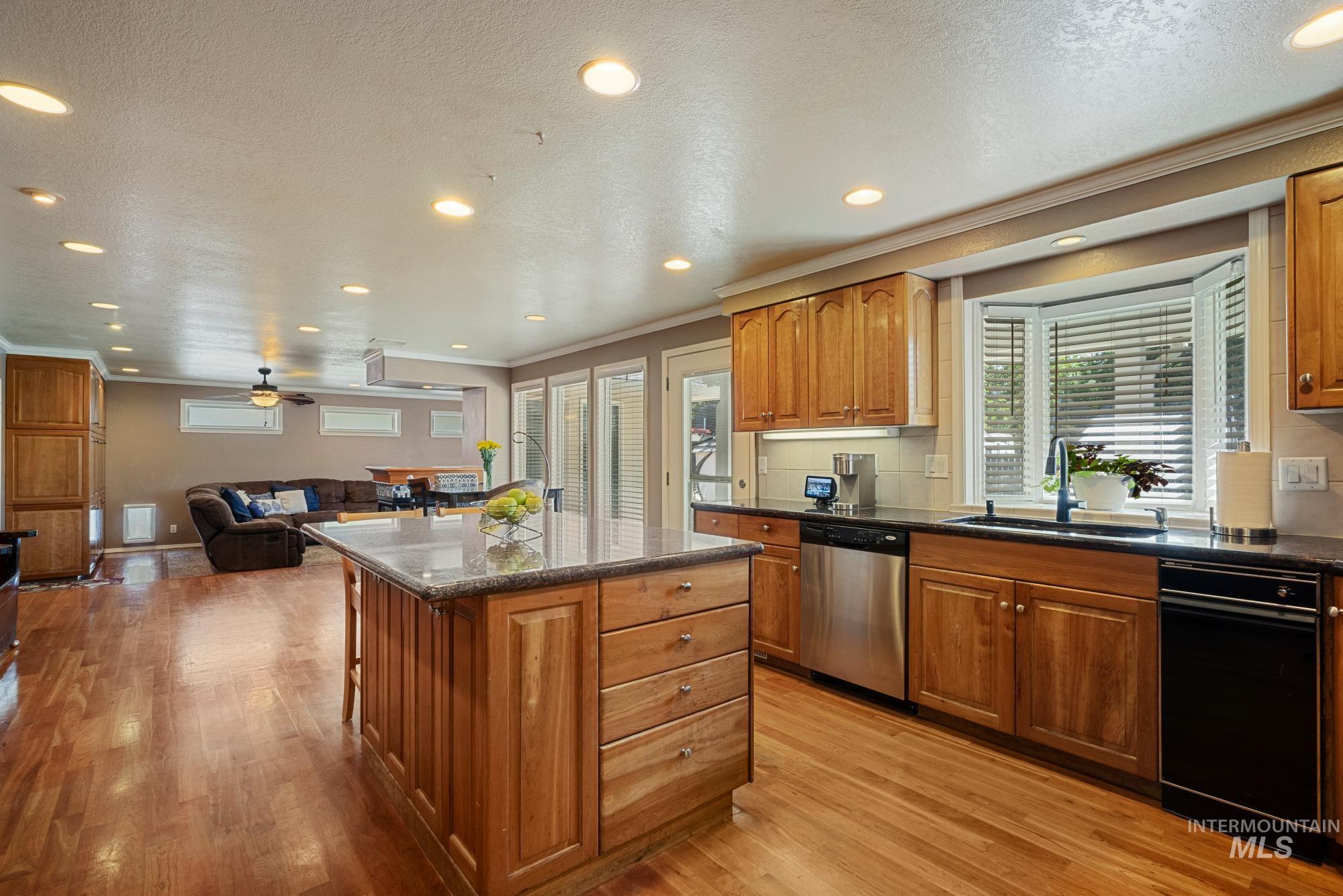 Kitchen featuring crown molding, recessed lighting, a textured ceiling, a center island, and a ceiling fan