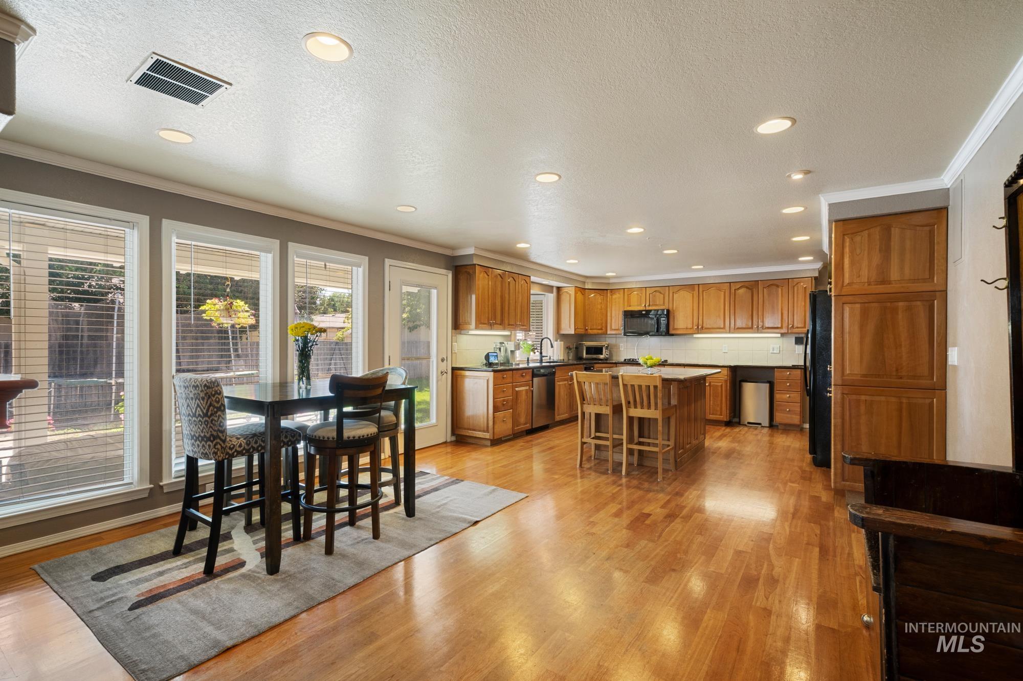 Dining space featuring crown molding, light wood finished floors, recessed lighting, and a textured ceiling