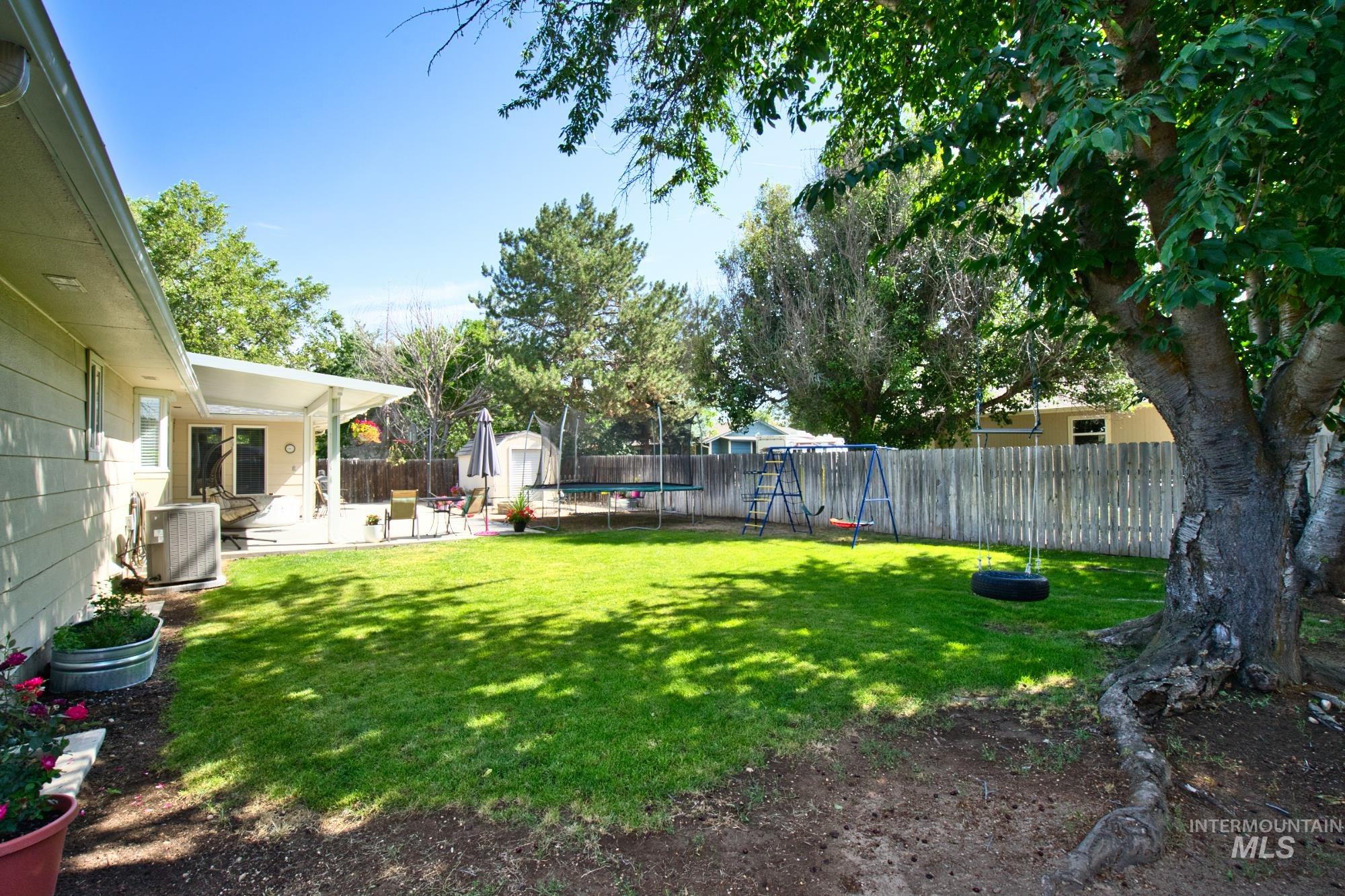 Fenced backyard featuring a shed, a patio area, and a trampoline