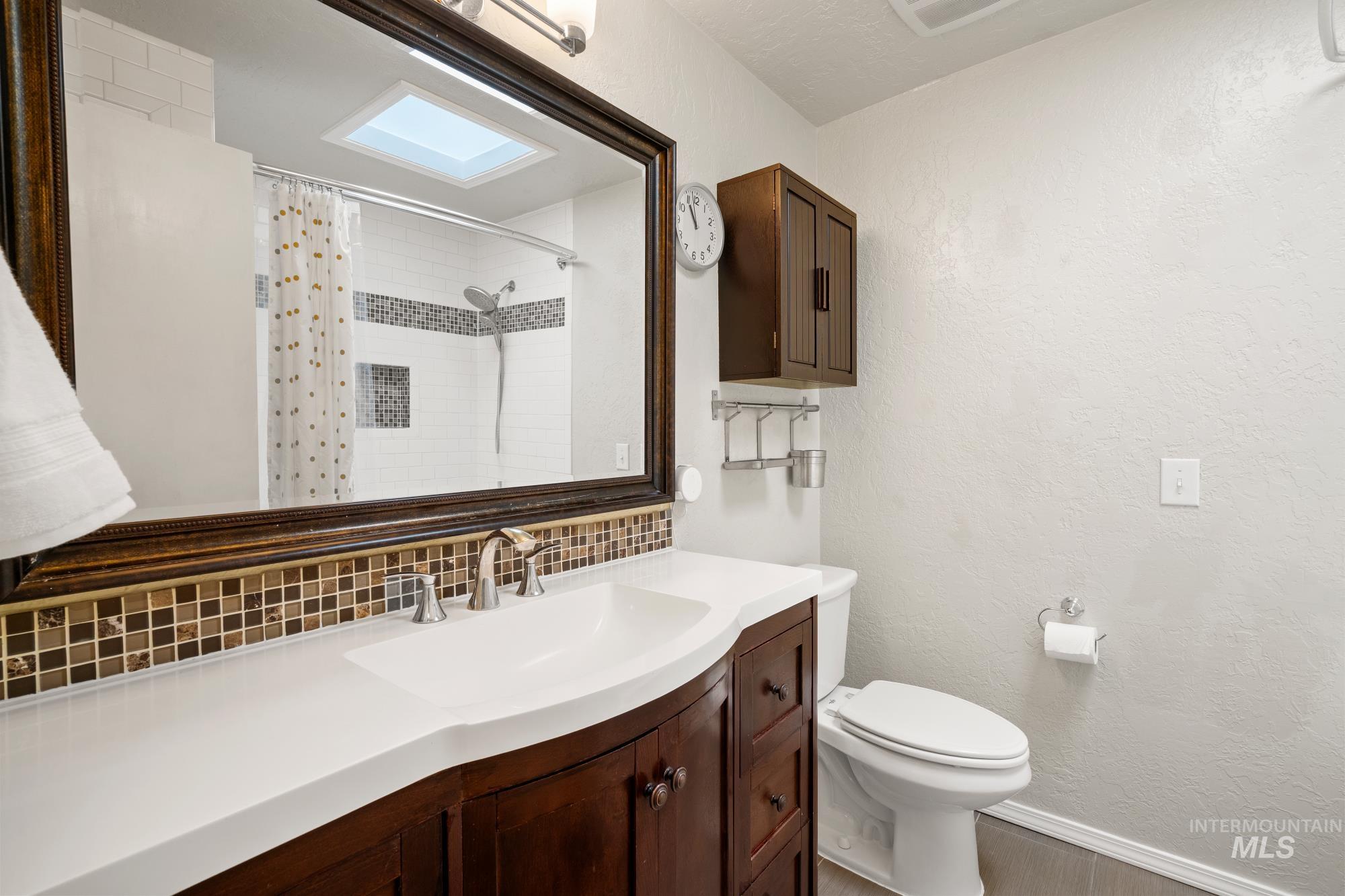 Bathroom with decorative backsplash, vanity, a shower with curtain, and a textured wall