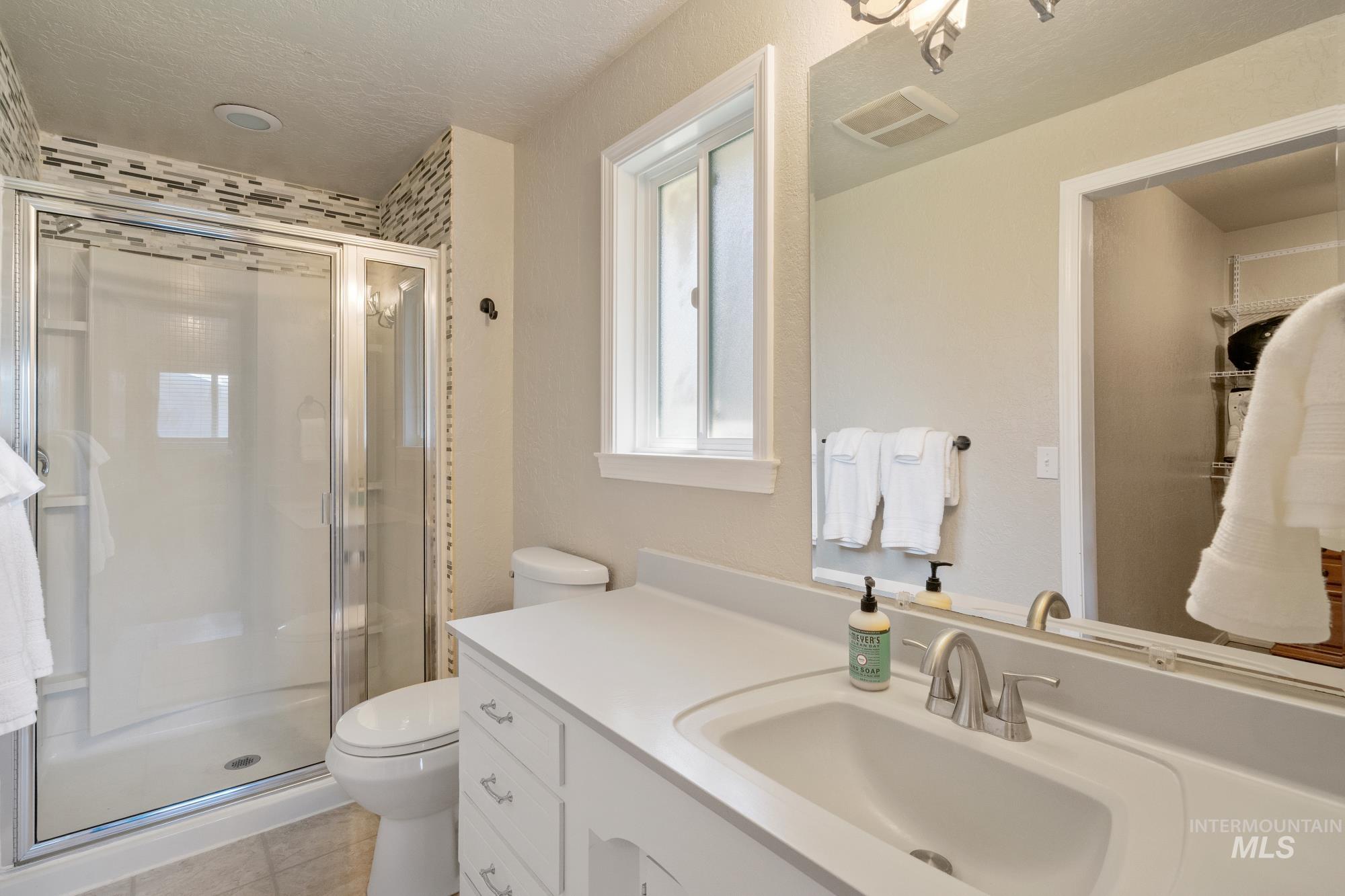 Bathroom with vanity, a stall shower, and tile patterned flooring