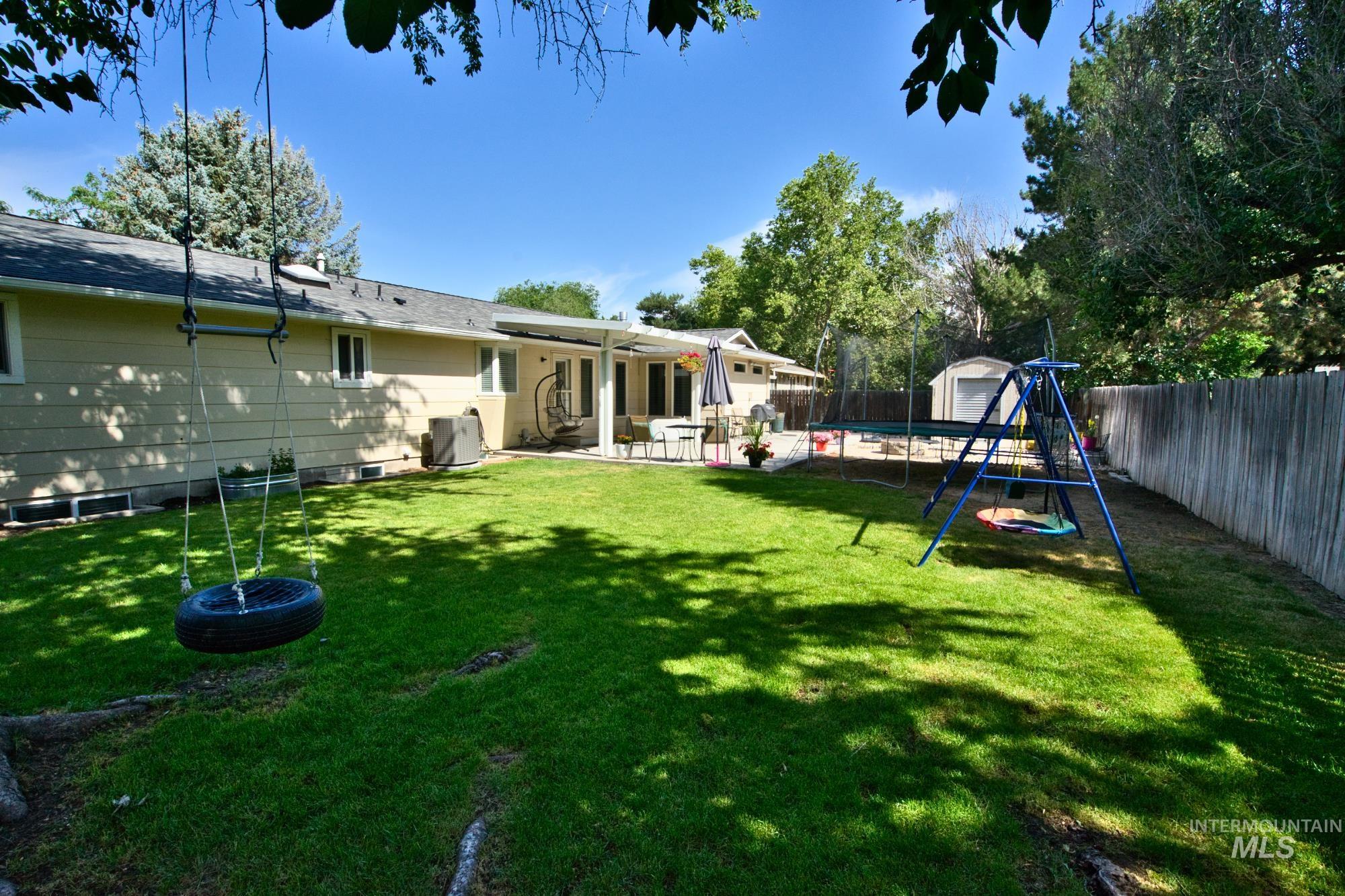 Fenced backyard with a storage unit and a patio