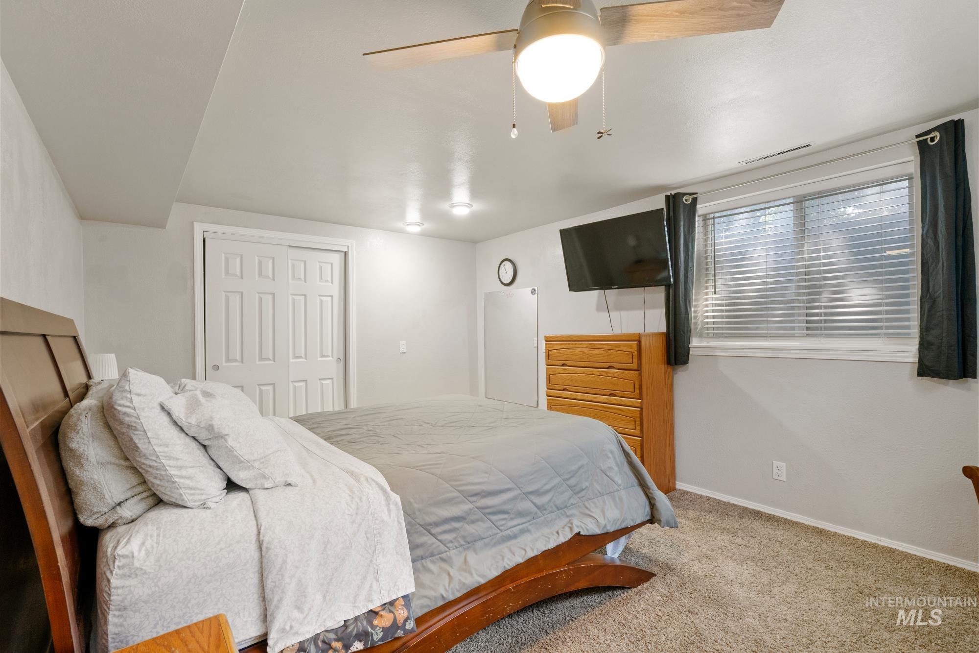 Carpeted bedroom with a closet and a ceiling fan