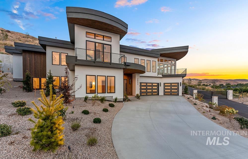 Contemporary house with a balcony, an attached garage, driveway, and stucco siding