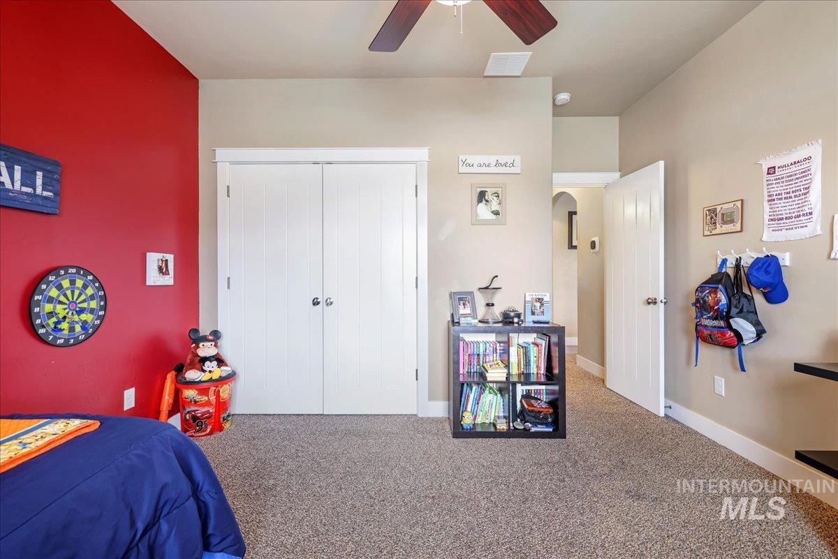 Bedroom featuring arched walkways, carpet flooring, a ceiling fan, and a closet