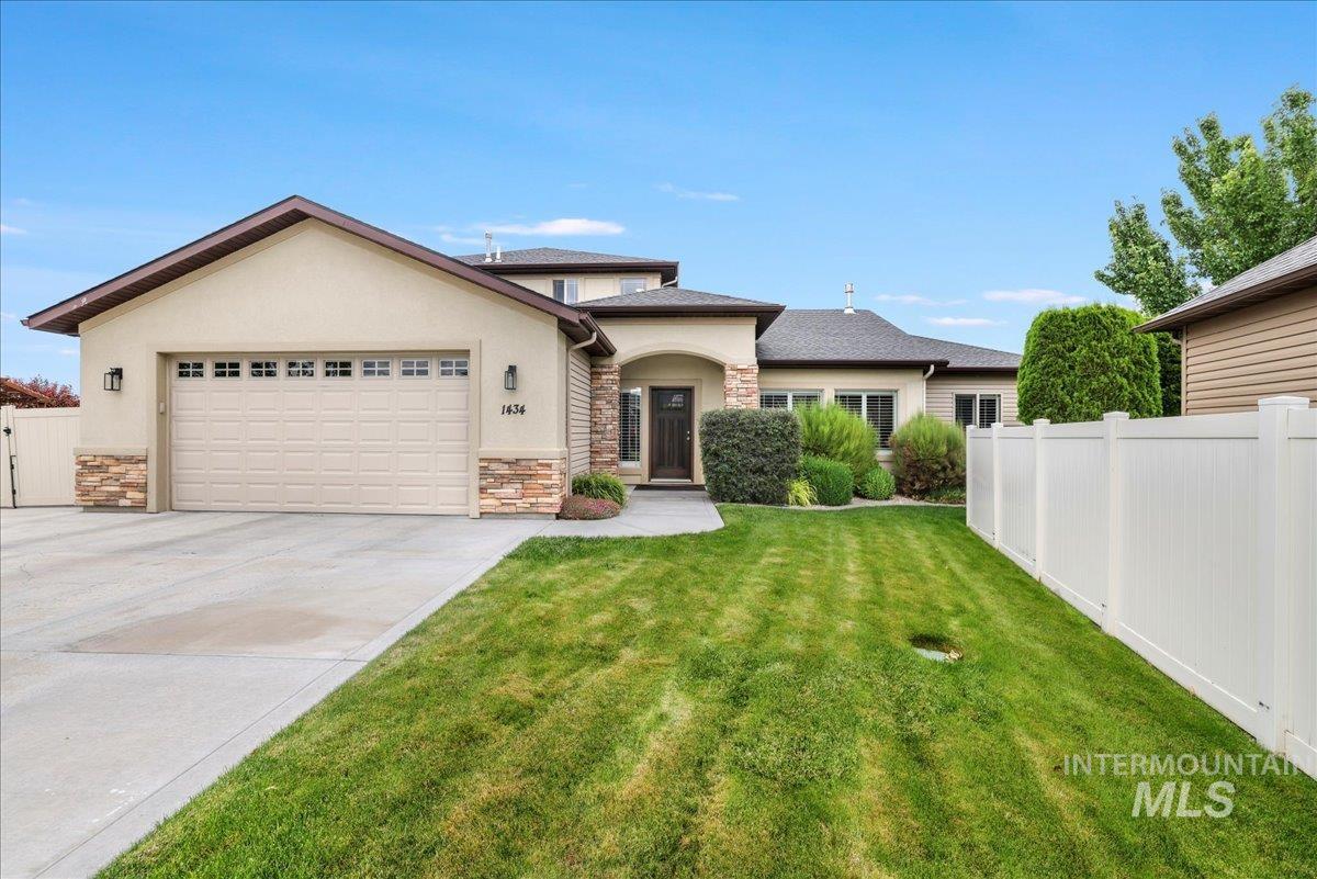 View of front facade with stone siding, stucco siding, an attached garage, and concrete driveway