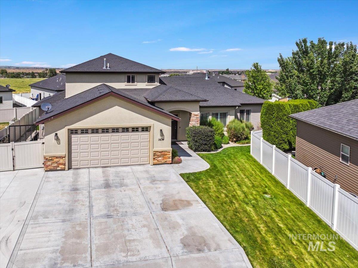 View of front of home with stone siding, stucco siding, driveway, roof with shingles, and an attached garage