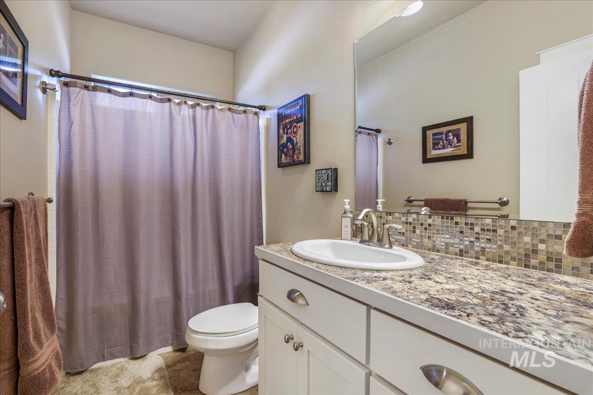 Full bathroom featuring vanity, decorative backsplash, and curtained shower