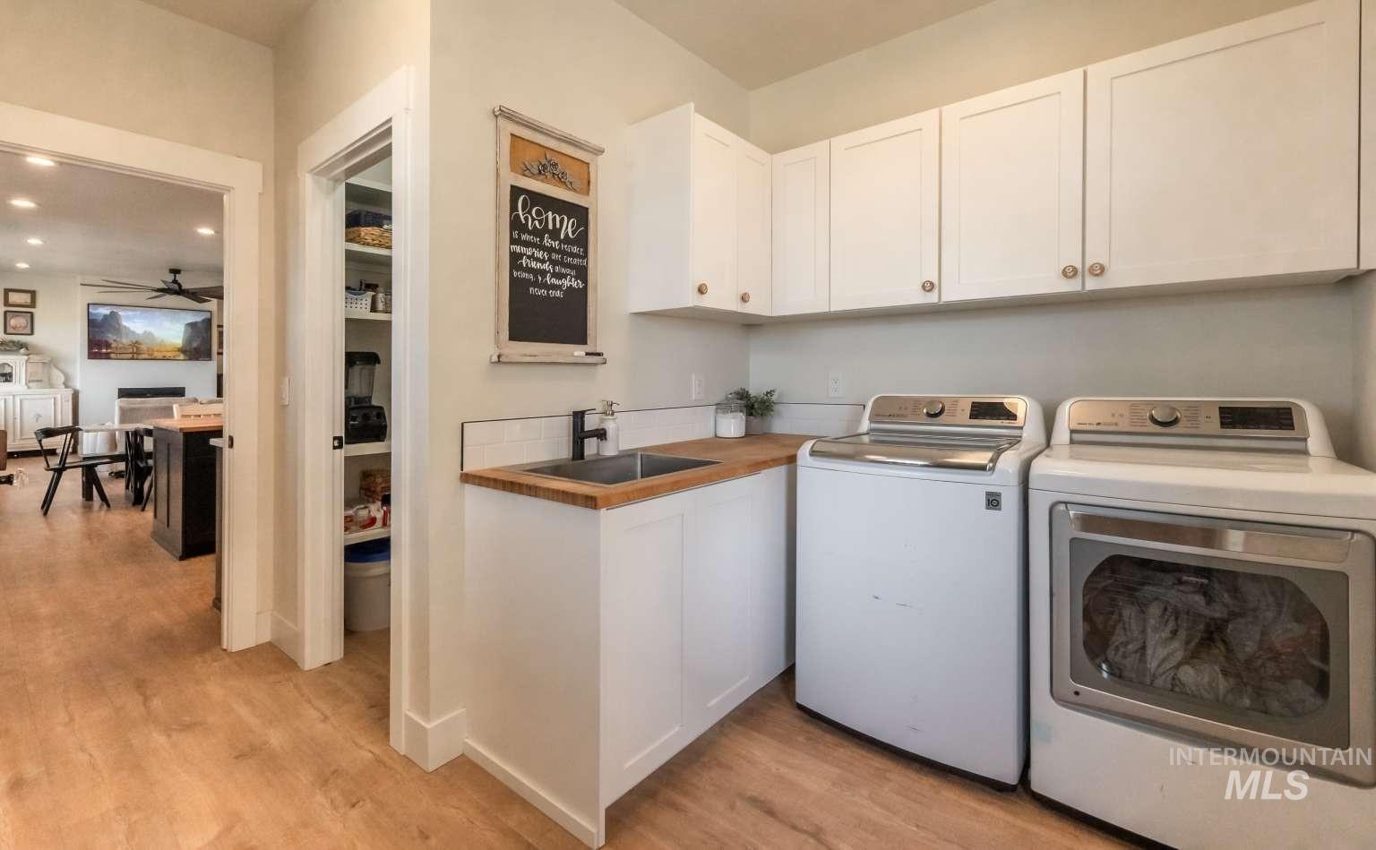 Washroom featuring washing machine and dryer, light wood-style floors, cabinet space, ceiling fan, and recessed lighting