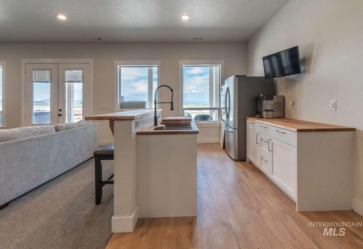 Kitchen with white cabinetry, wooden counters, a kitchen bar, a kitchen island with sink, and open floor plan