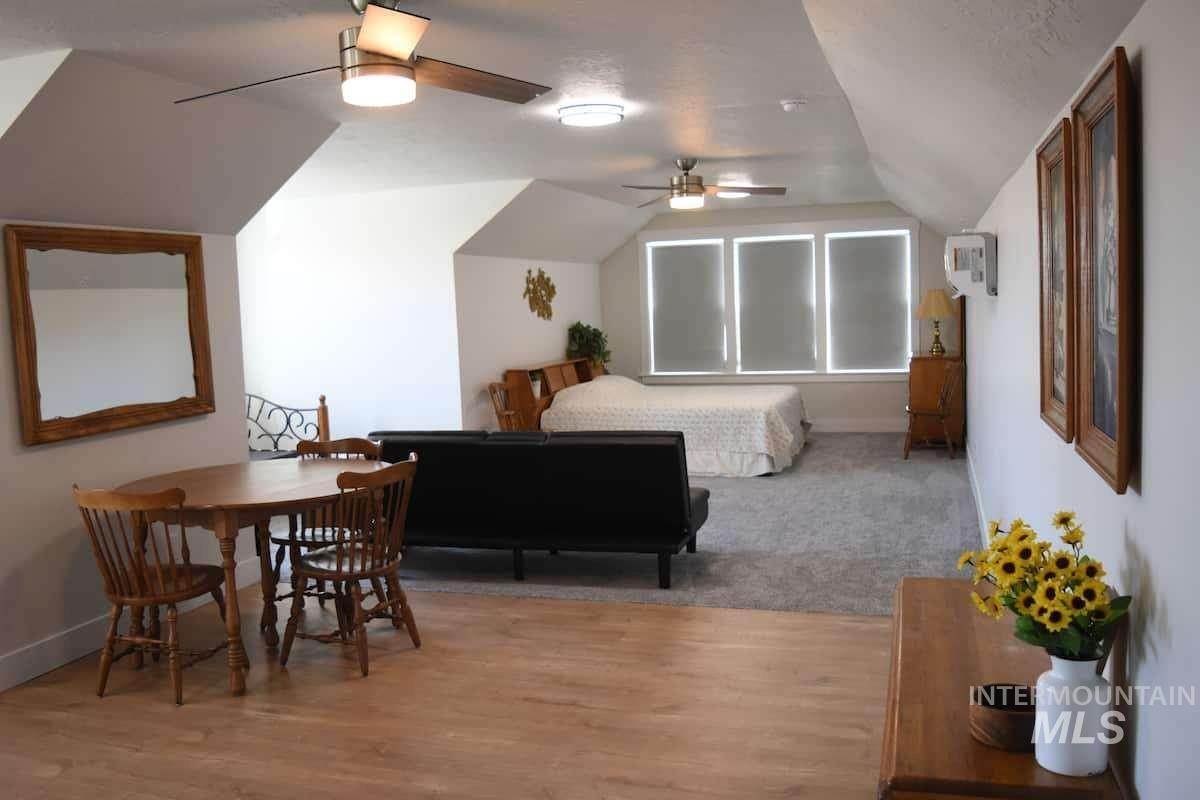 Bedroom with vaulted ceiling, light wood-type flooring, and a ceiling fan