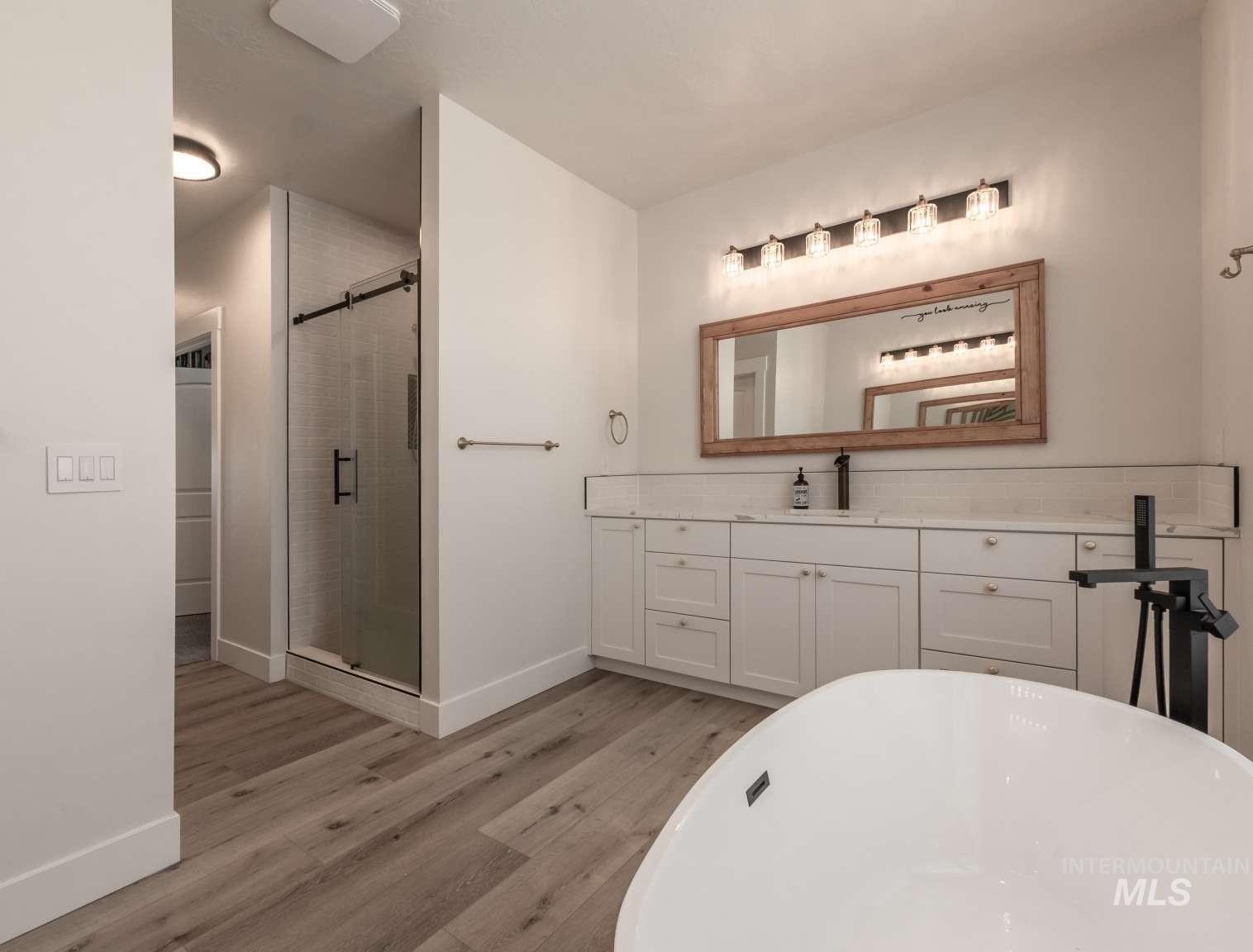 Full bath with vanity, a stall shower, a soaking tub, and light wood-type flooring
