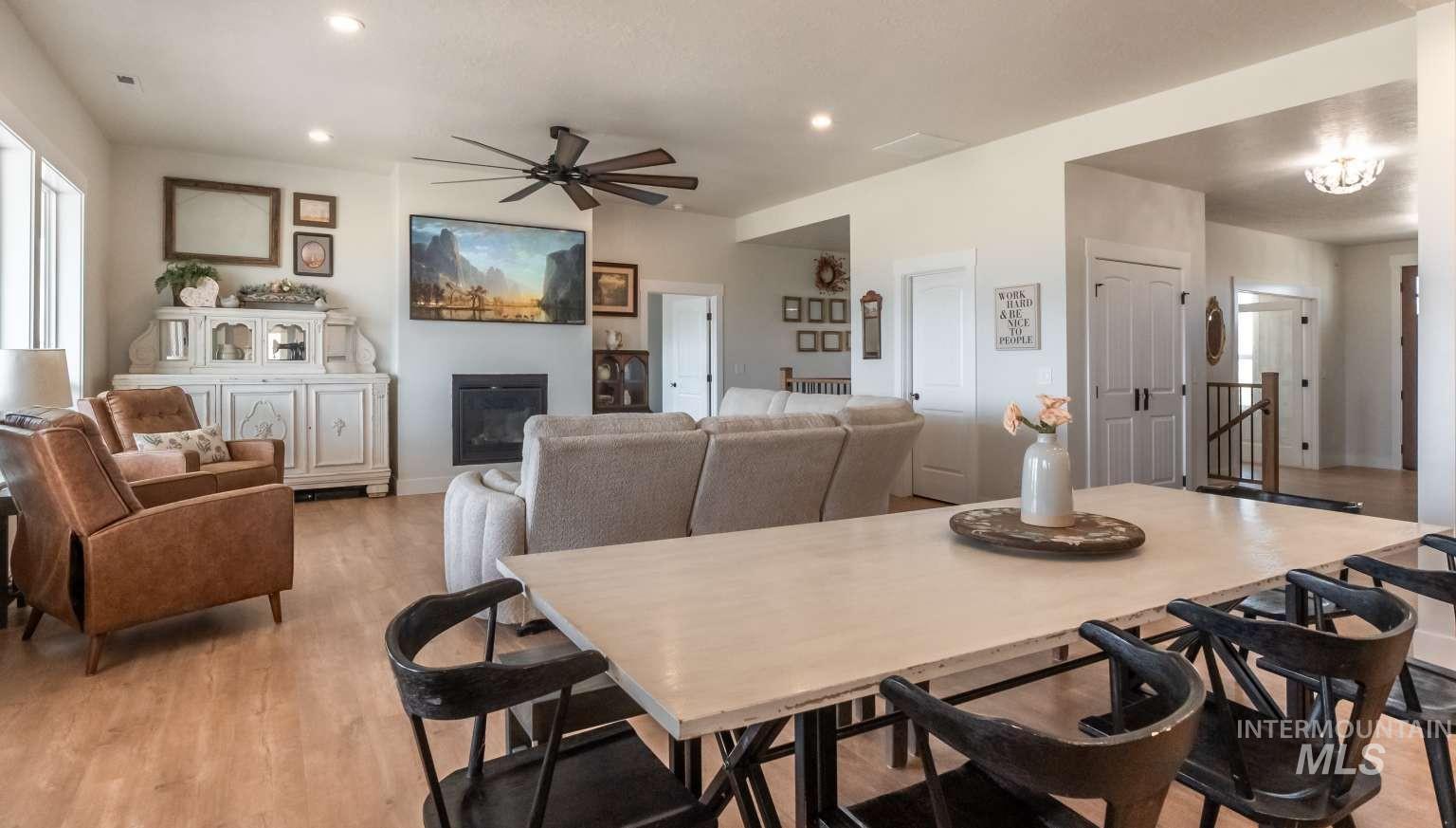 Dining area with a glass covered fireplace, light wood-style floors, ceiling fan, and recessed lighting