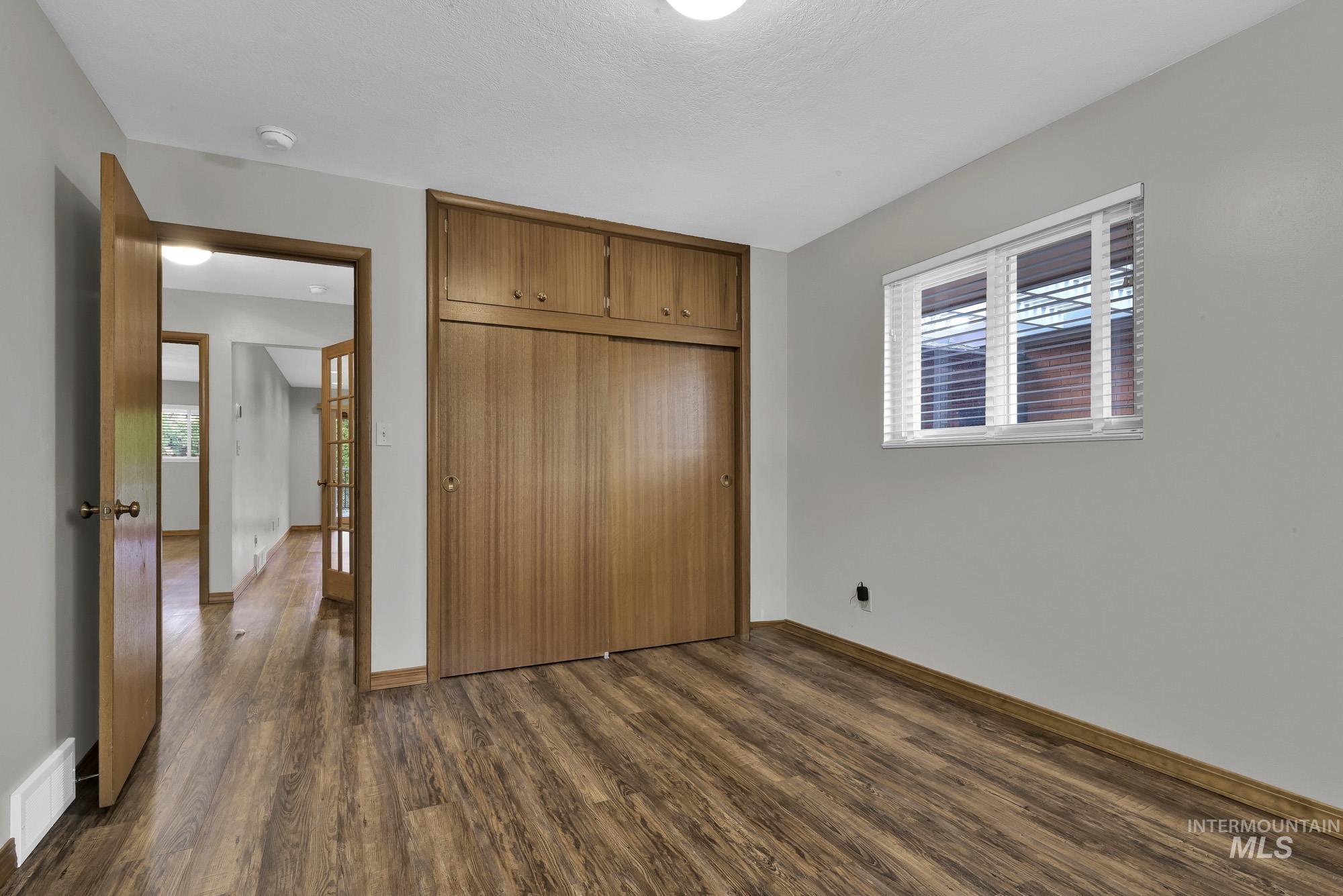 Unfurnished bedroom featuring dark wood-style floors and a closet