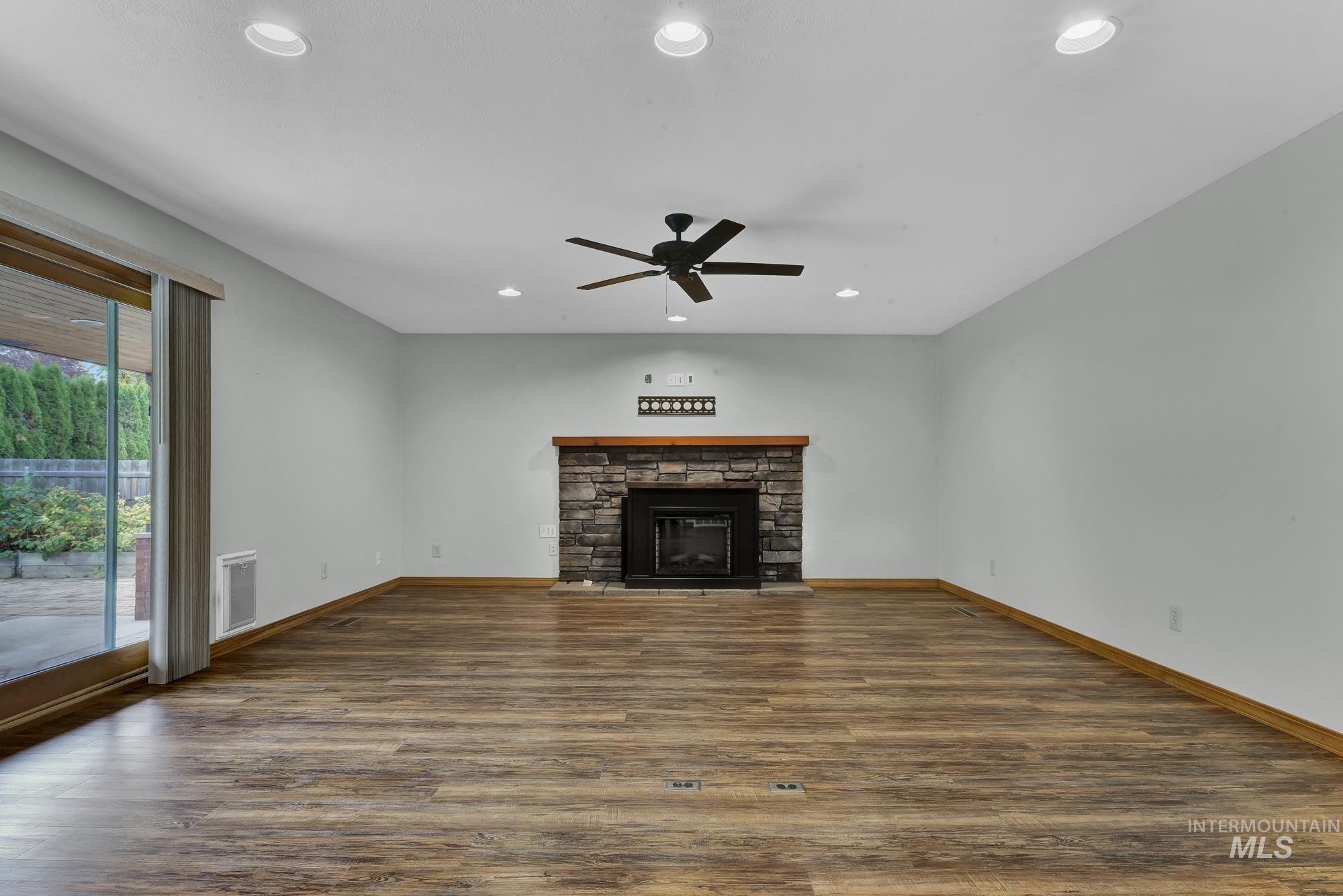Unfurnished living room featuring recessed lighting, dark wood-style floors, a fireplace, and a ceiling fan