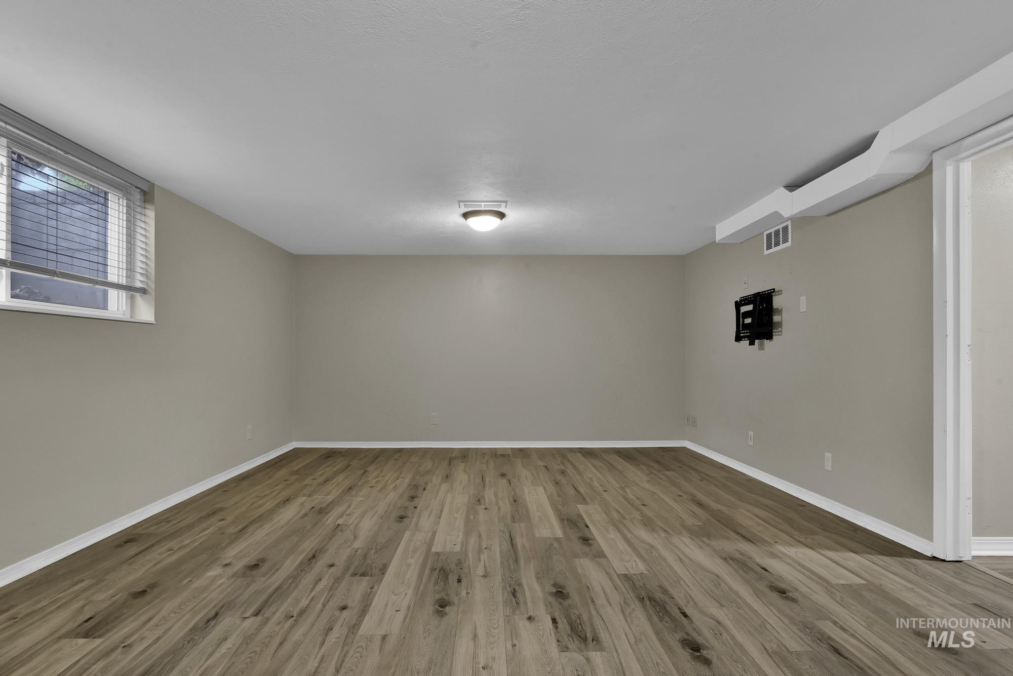 Spare room featuring wood finished floors and baseboards
