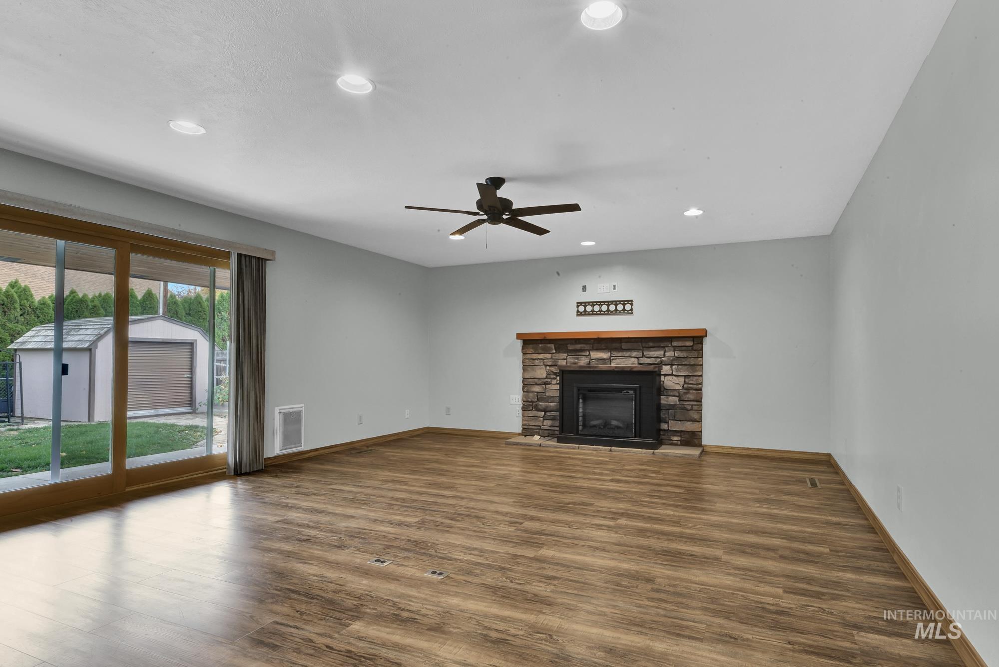 Unfurnished living room with recessed lighting, wood finished floors, a stone fireplace, and a ceiling fan