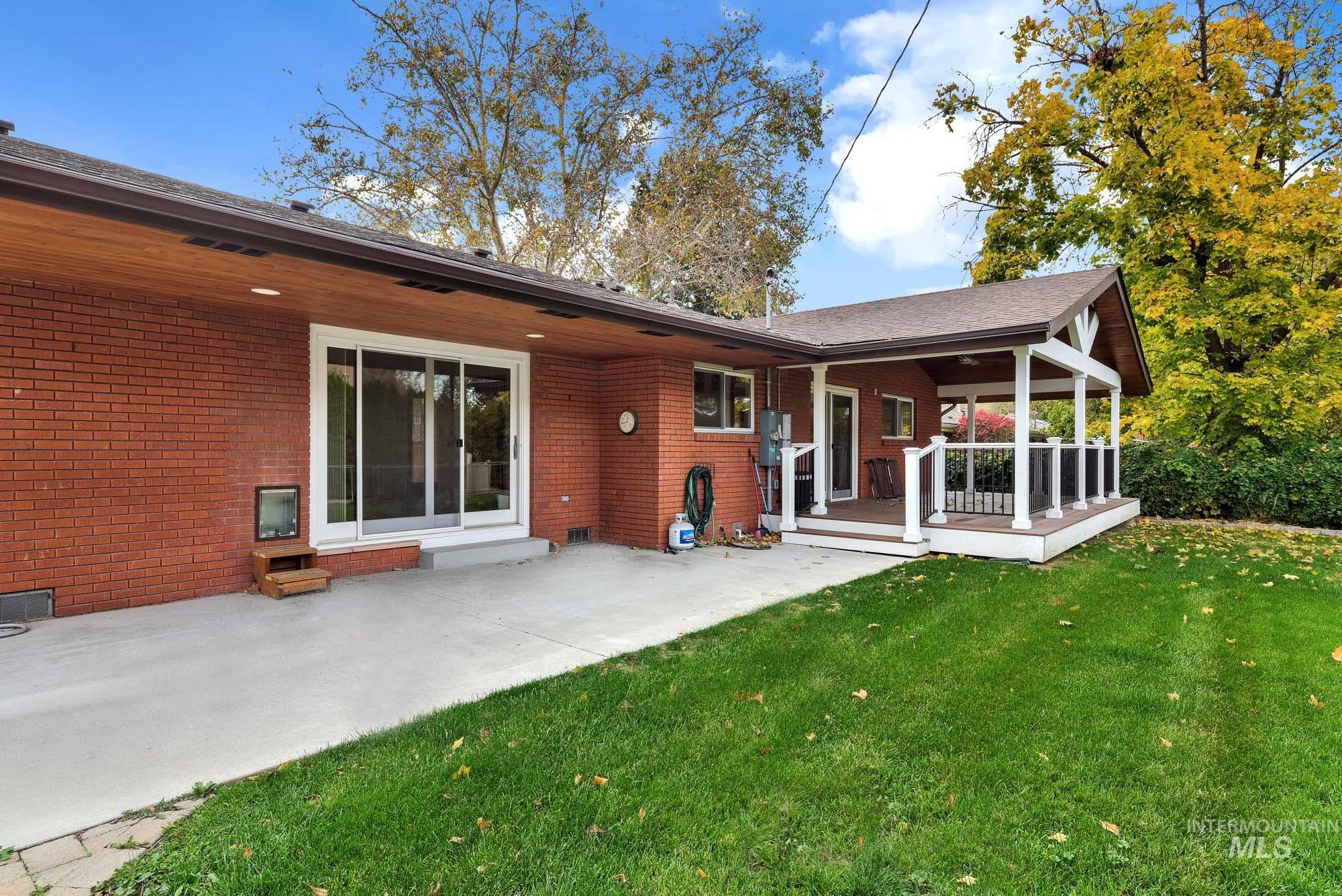 Rear view of house featuring a yard, brick siding, a patio, and a deck