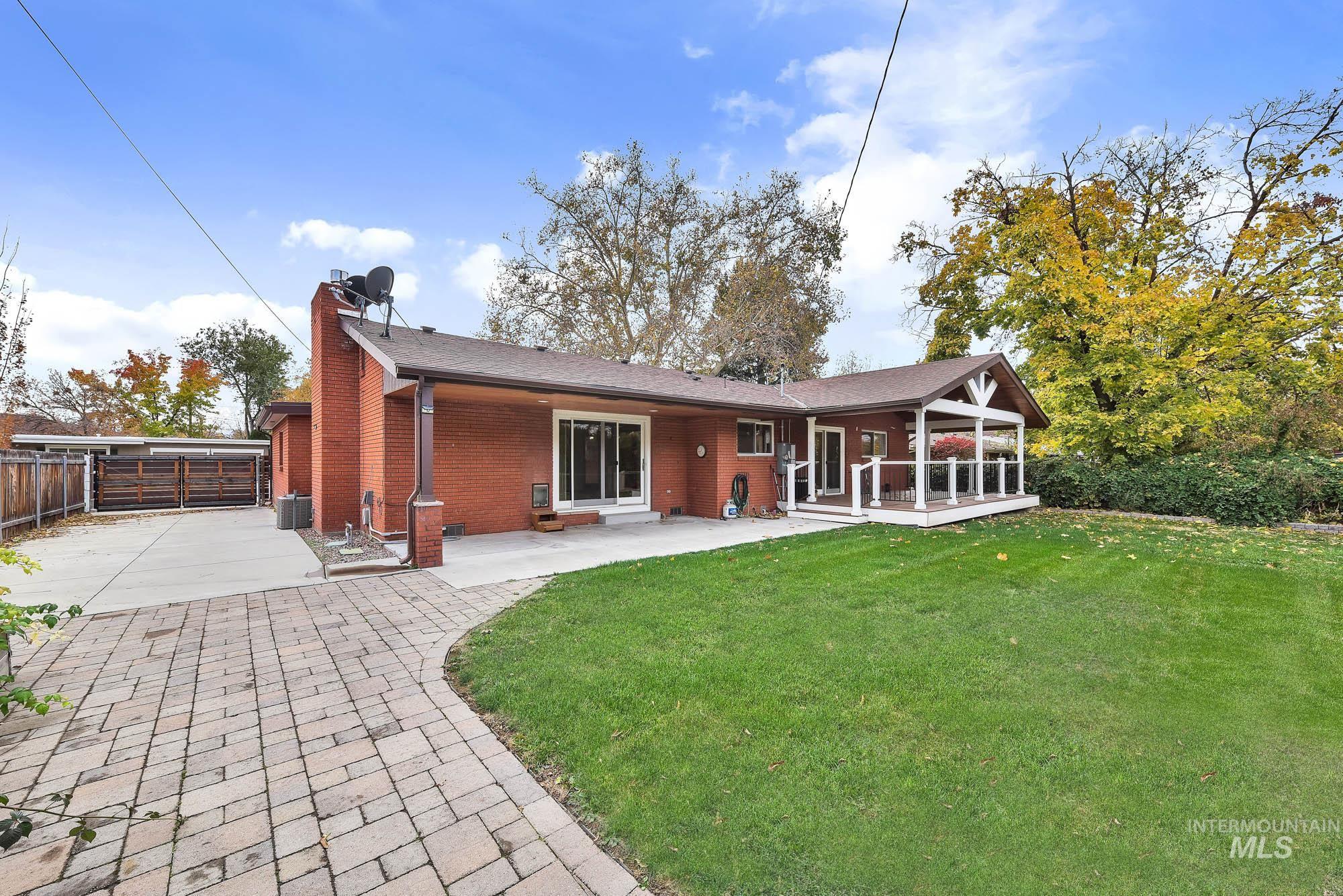 Rear view of house with a chimney, brick siding, and driveway
