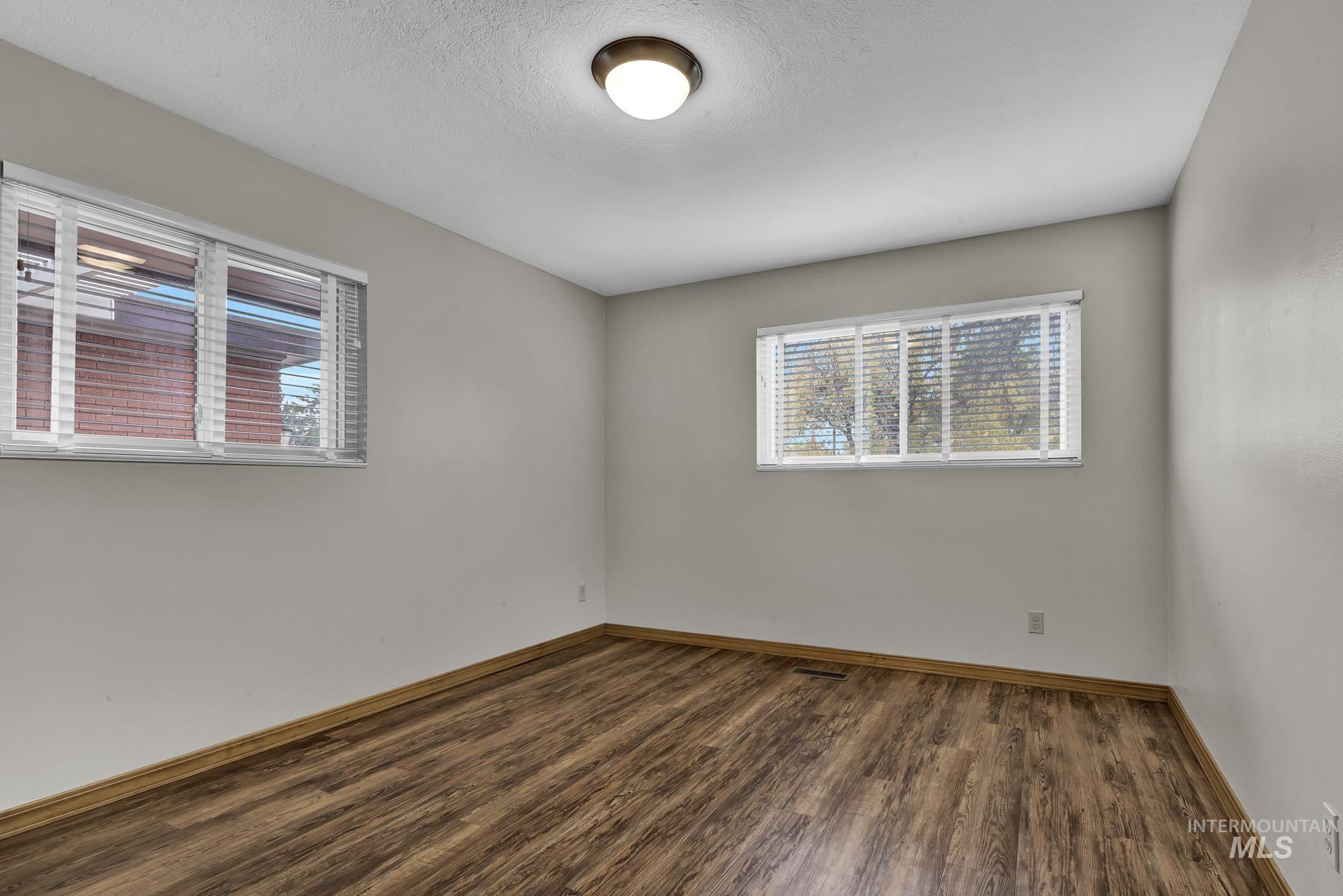 Spare room featuring dark wood-type flooring and a textured ceiling