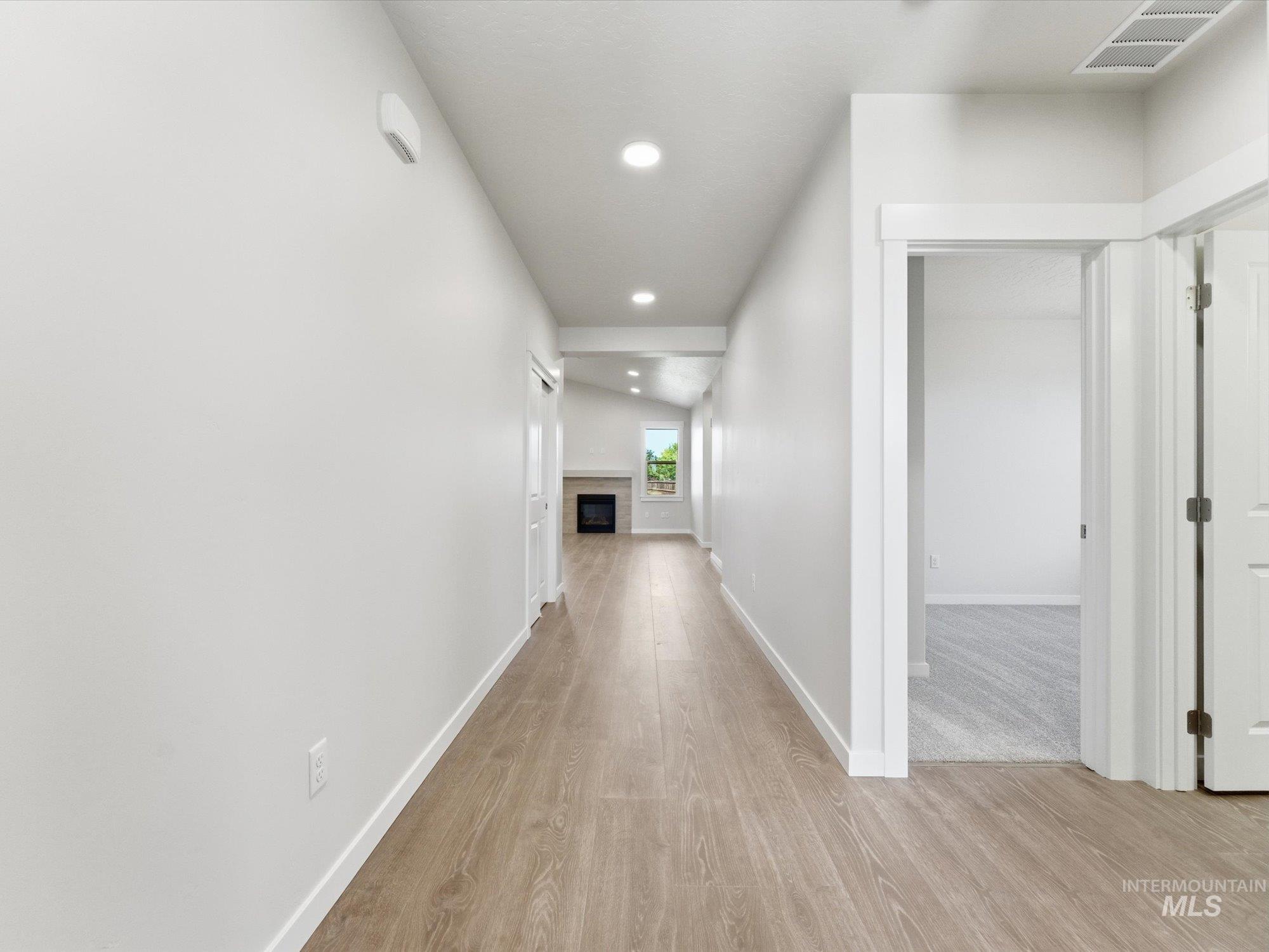 Long hallway featuring wood-finish flooring and recessed lighting