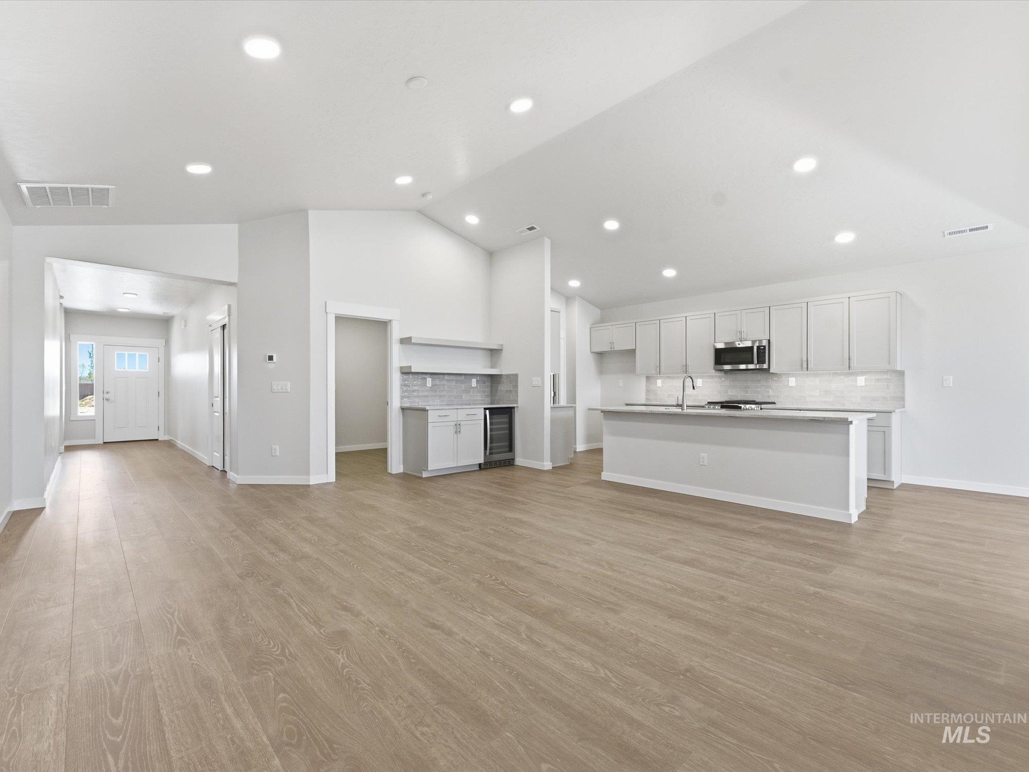 Spacious open-concept living area featuring light wood-finish flooring and recessed lighting