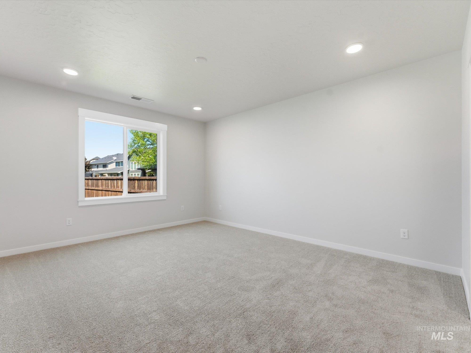 Spacious interior room featuring light gray carpeting and white painted walls