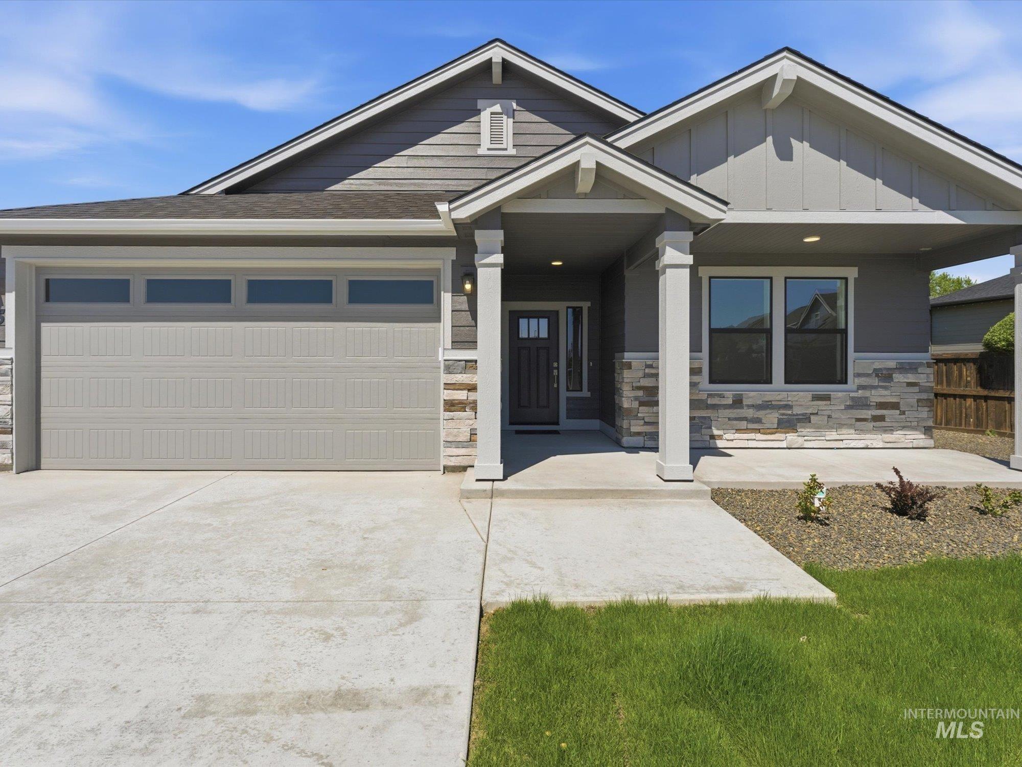 Contemporary exterior featuring a covered entry, stone veneer accents, and a two-car garage with transom windows