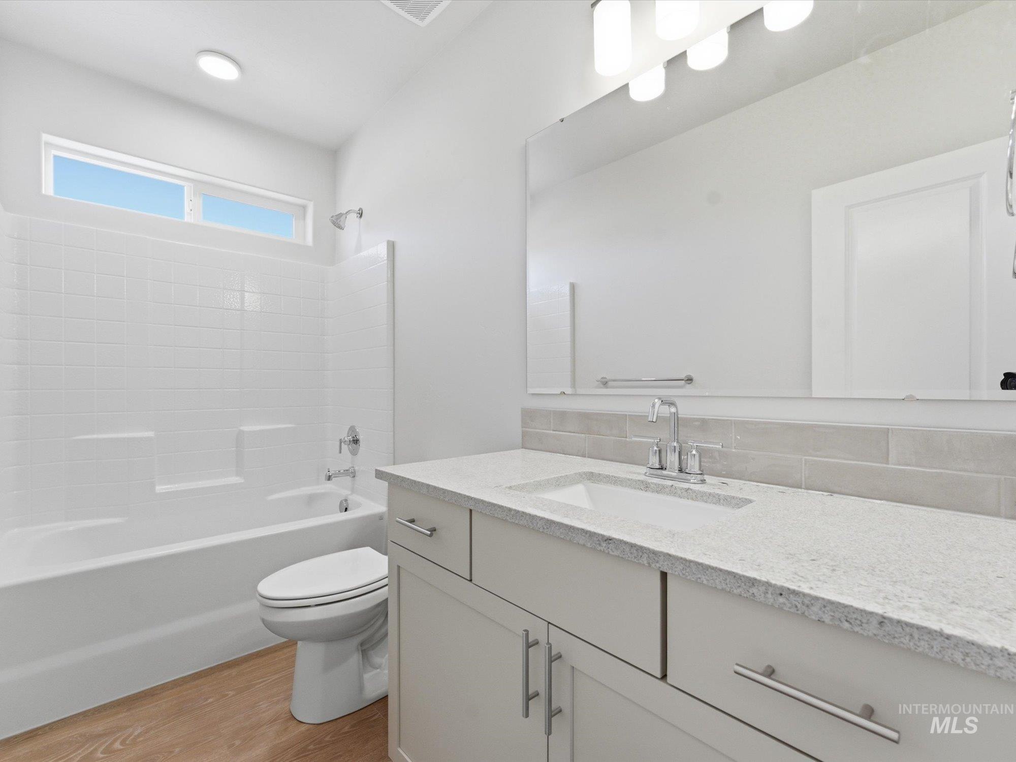 Bathroom vanity featuring a light-toned countertop with integrated sink and chrome fixtures