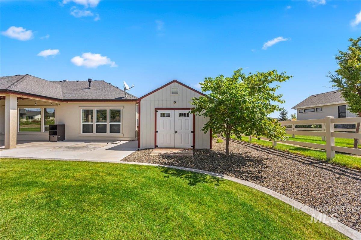 Back of house with an outdoor structure and a patio