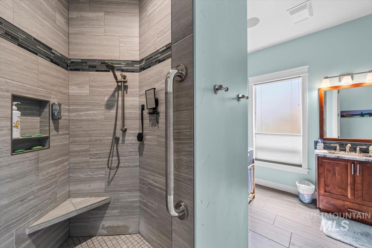 Full bathroom with vanity, a tile shower, and light wood-type flooring