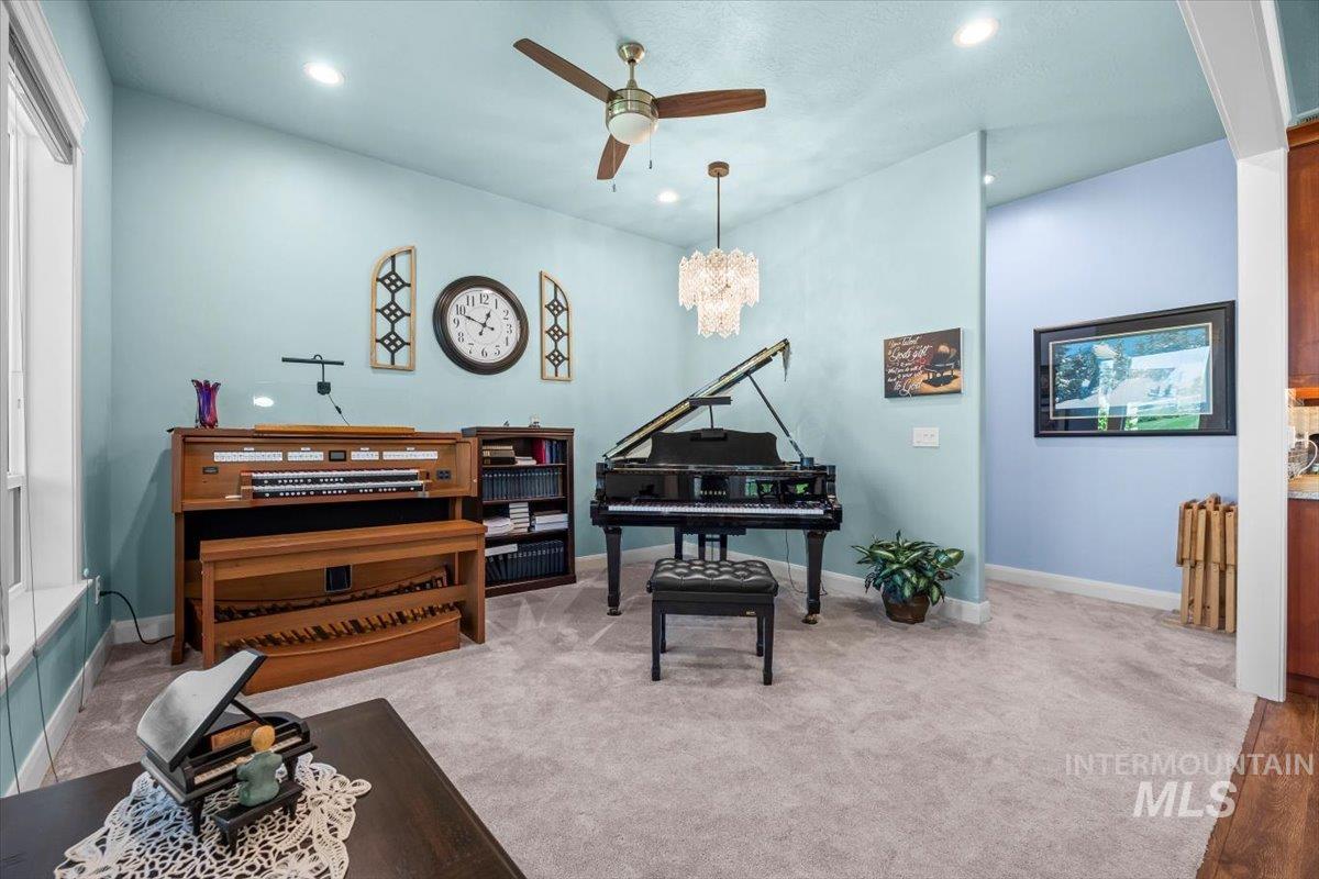 Living area featuring light colored carpet, ceiling fan, recessed lighting, and a chandelier