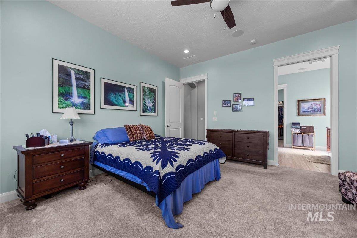 Bedroom featuring carpet, a textured ceiling, and ceiling fan