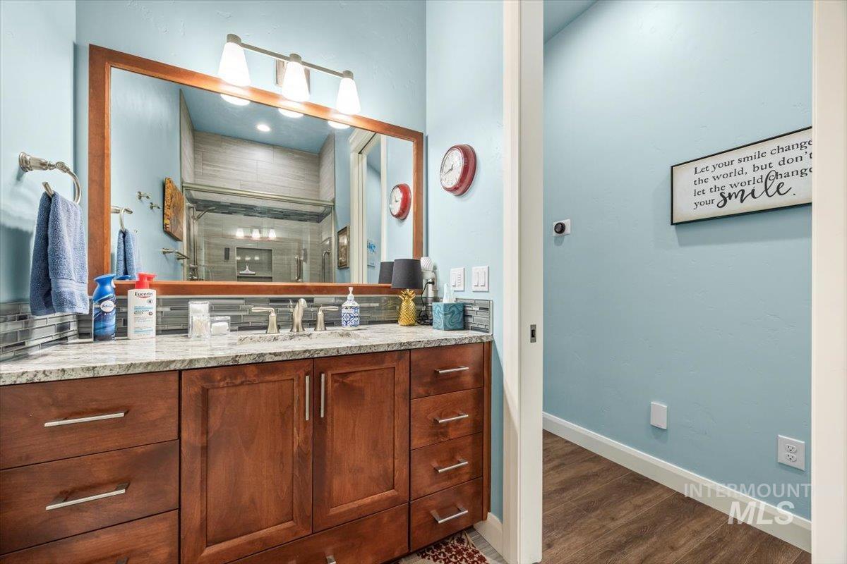 Full bath with vanity, a shower stall, and dark wood-style flooring