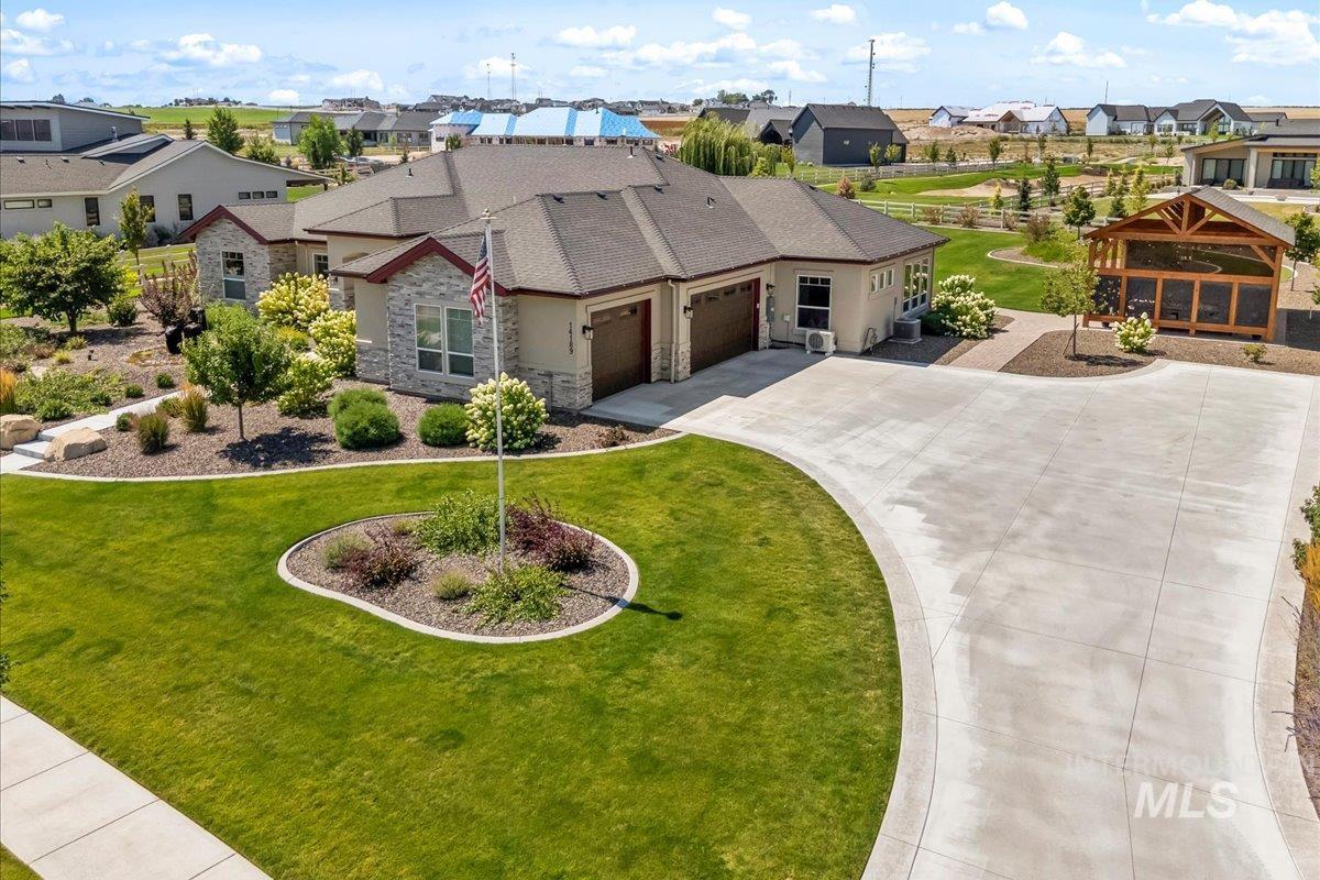 View of front of property with stone siding, a residential view, an attached garage, and curved driveway