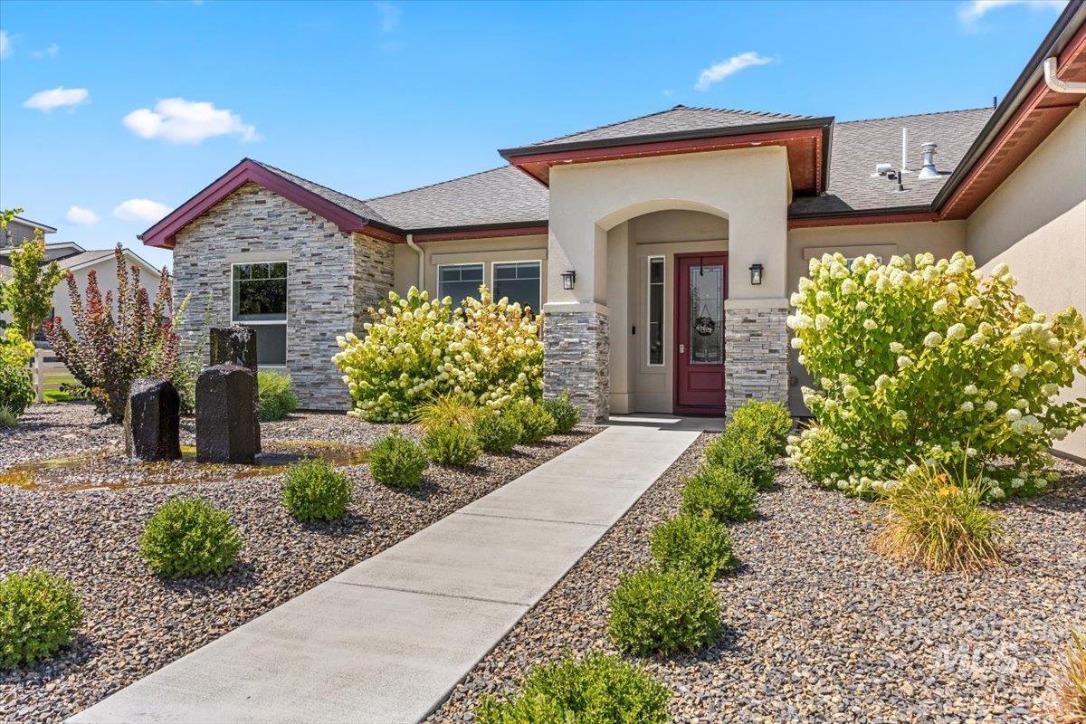 Entrance to property with stone siding, stucco siding, and roof with shingles