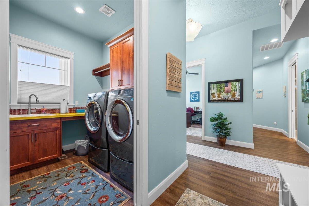 Washroom with dark wood-style flooring, cabinet space, independent washer and dryer, and recessed lighting