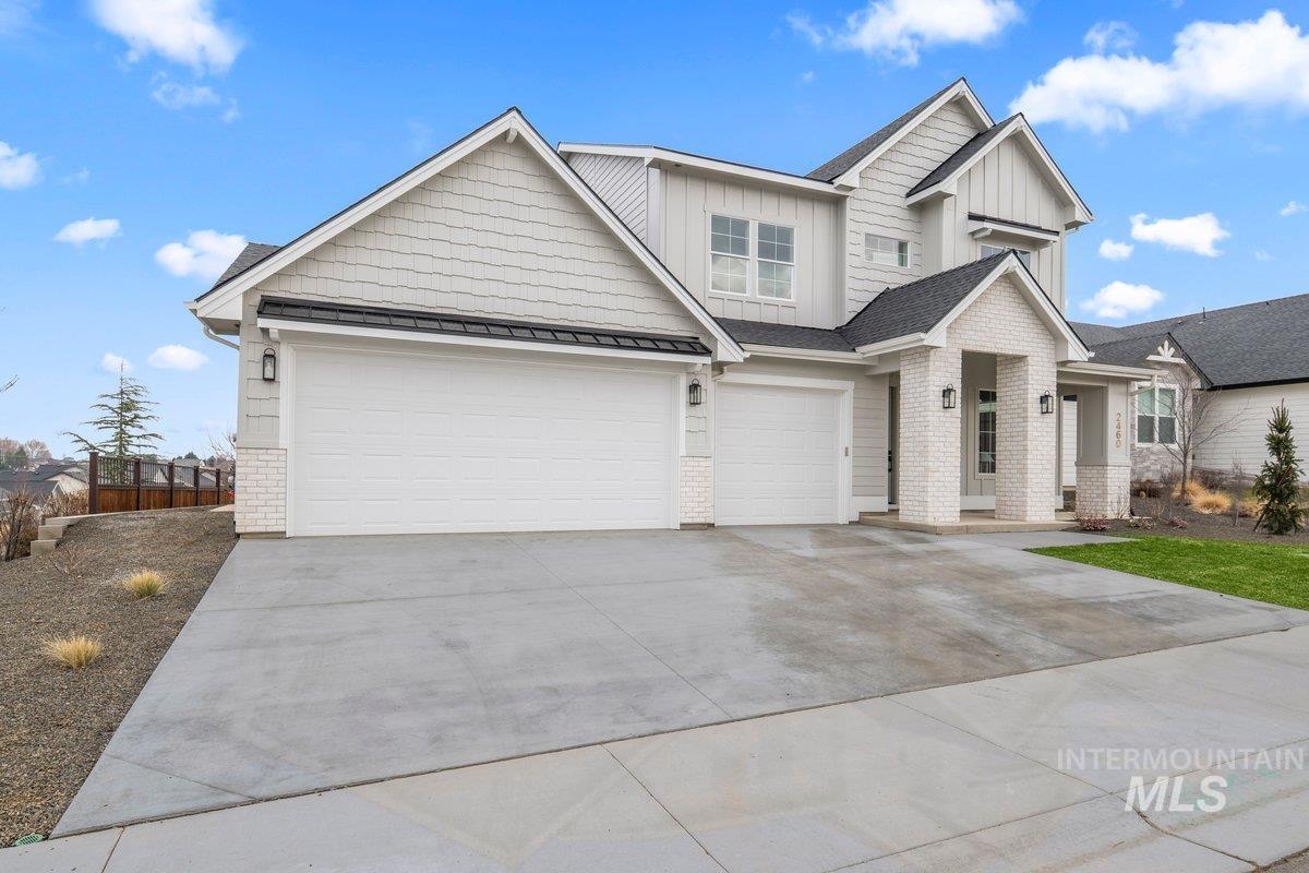 Craftsman house with brick siding, driveway, board and batten siding, and a metal roof