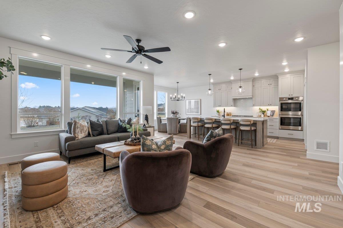 Living area with light wood-type flooring, a chandelier, ceiling fan, and recessed lighting