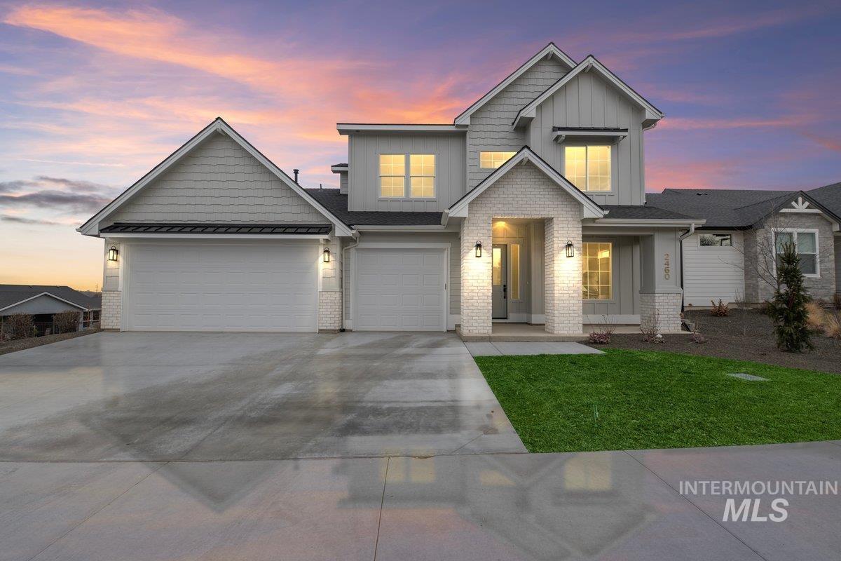 Craftsman inspired home with board and batten siding, driveway, brick siding, a lawn, and a metal roof