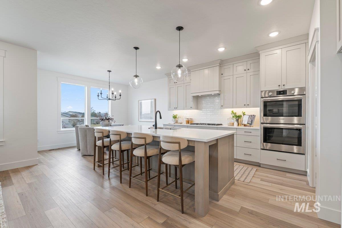 Kitchen with a breakfast bar area, stainless steel appliances, a chandelier, pendant lighting, and an island with sink