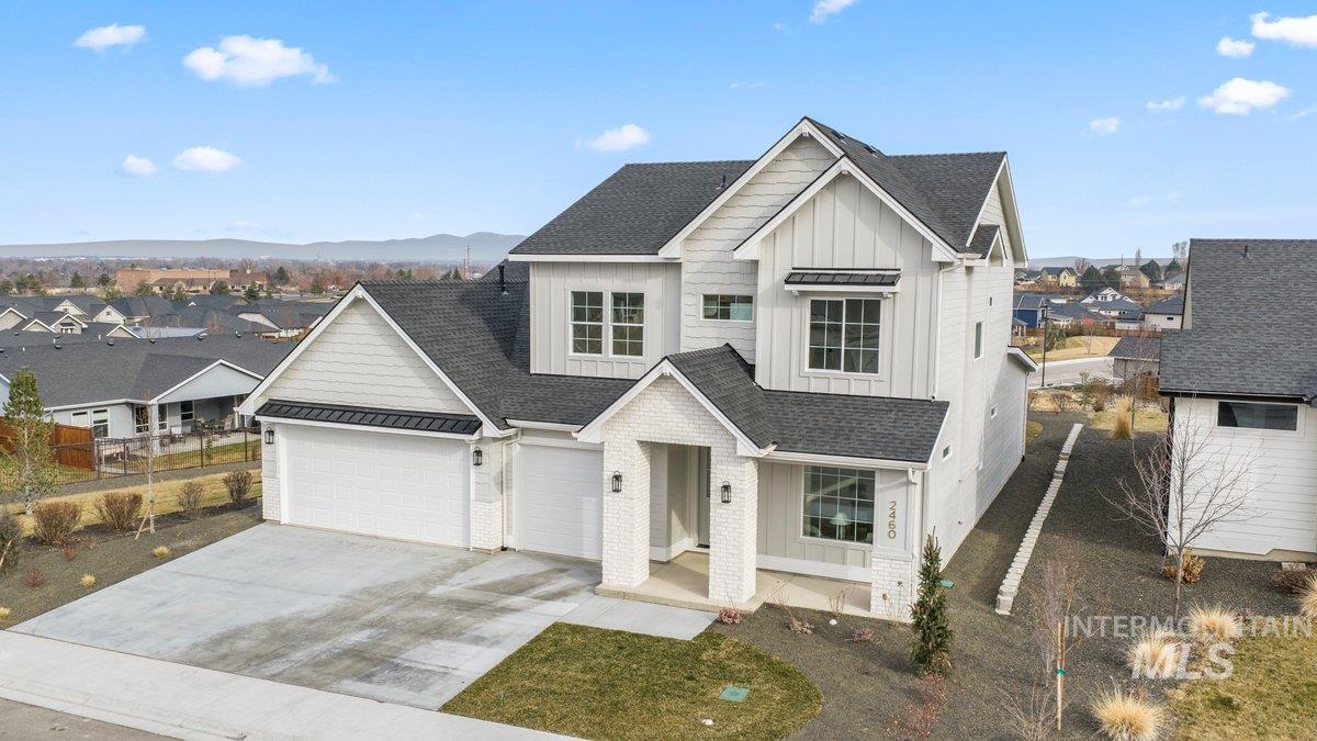 View of front of property featuring board and batten siding, concrete driveway, a shingled roof, and a residential view