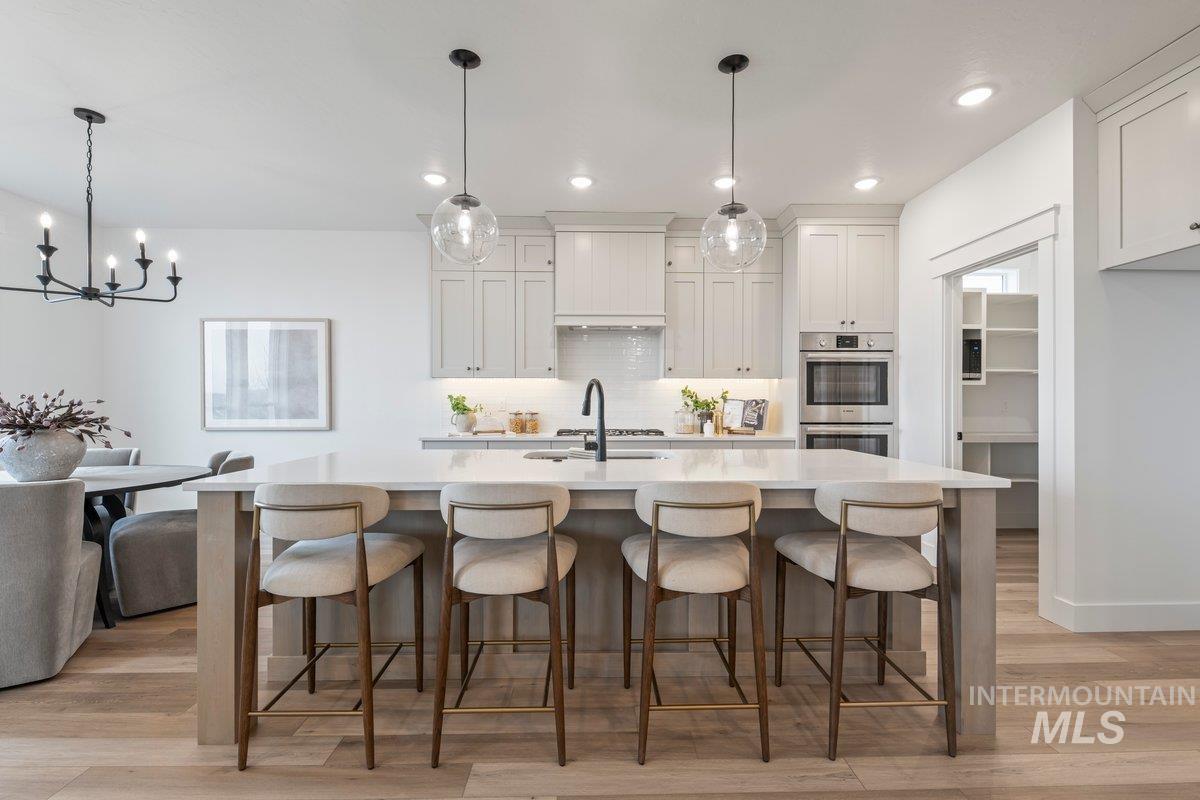 Kitchen with light wood-type flooring, decorative backsplash, a breakfast bar, recessed lighting, and white cabinets