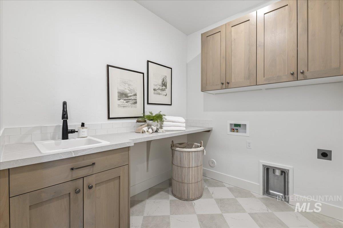 Washroom with cabinet space, washer hookup, hookup for an electric dryer, and light flooring