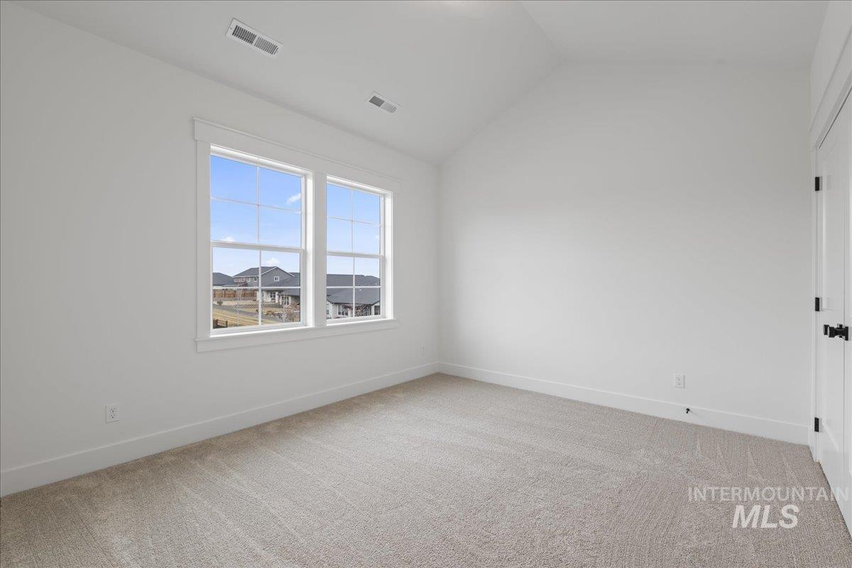 Spare room featuring light colored carpet and vaulted ceiling