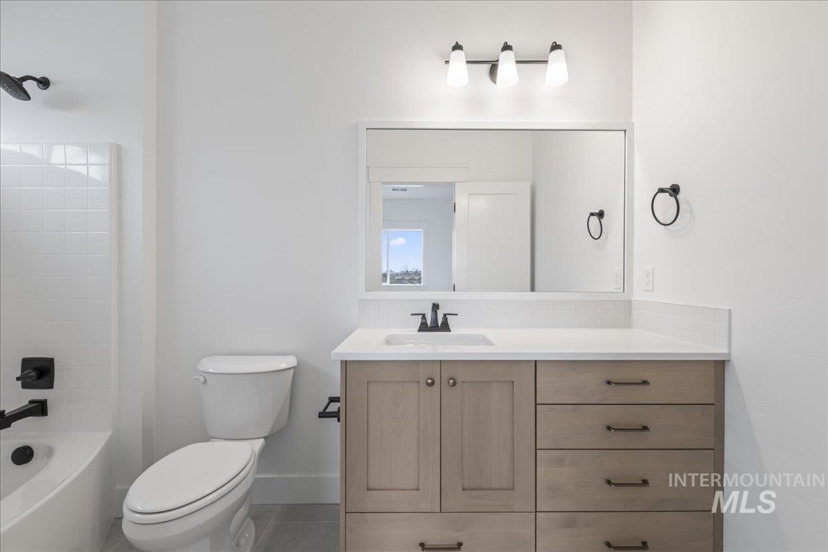 Bathroom with vanity, tub / shower combination, decorative backsplash, and tile patterned flooring