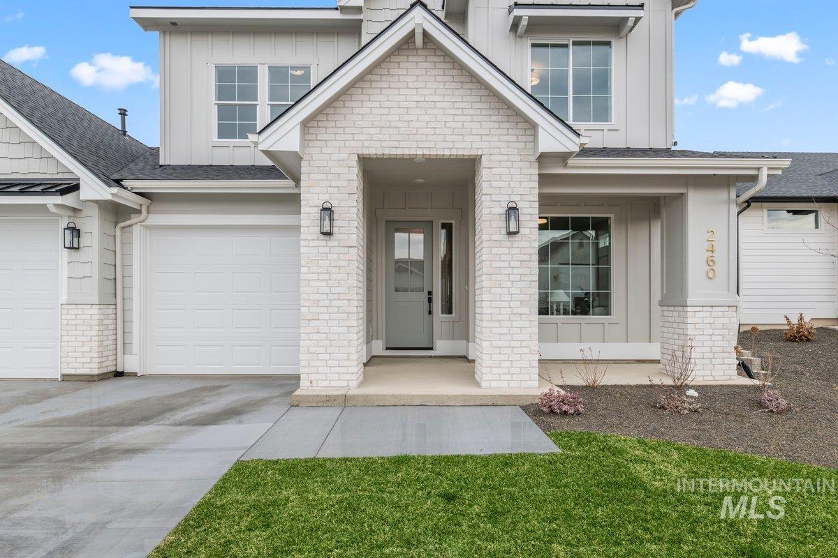 View of front of house with board and batten siding, driveway, brick siding, and a porch