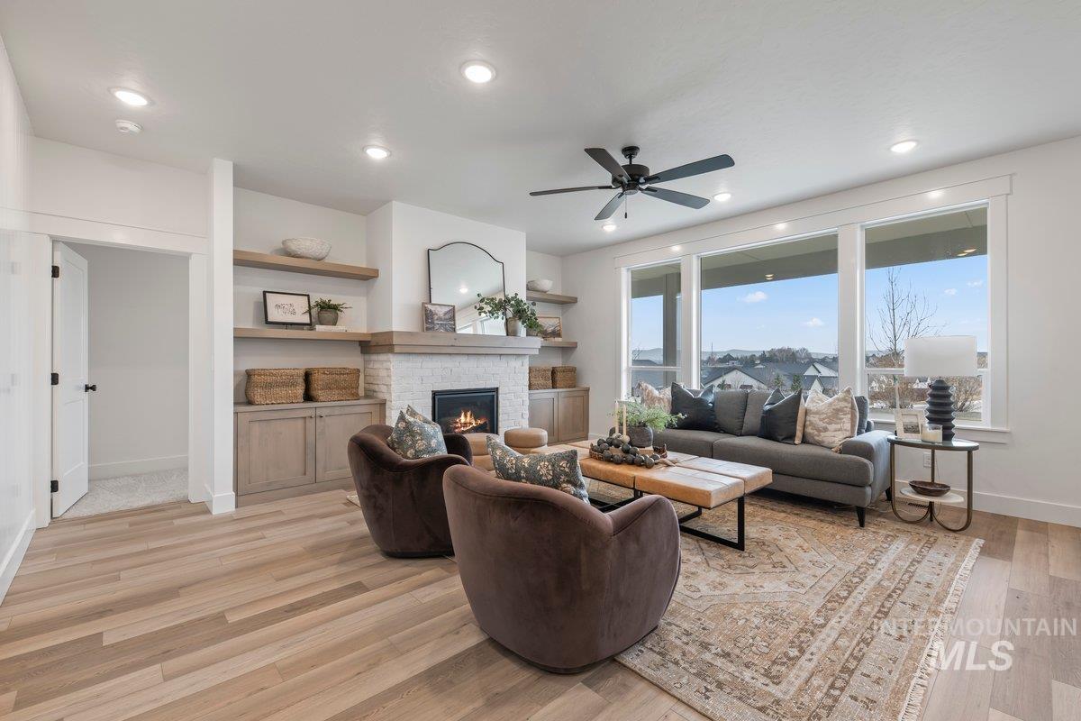 Living area featuring light wood-style floors, a fireplace, a ceiling fan, and recessed lighting